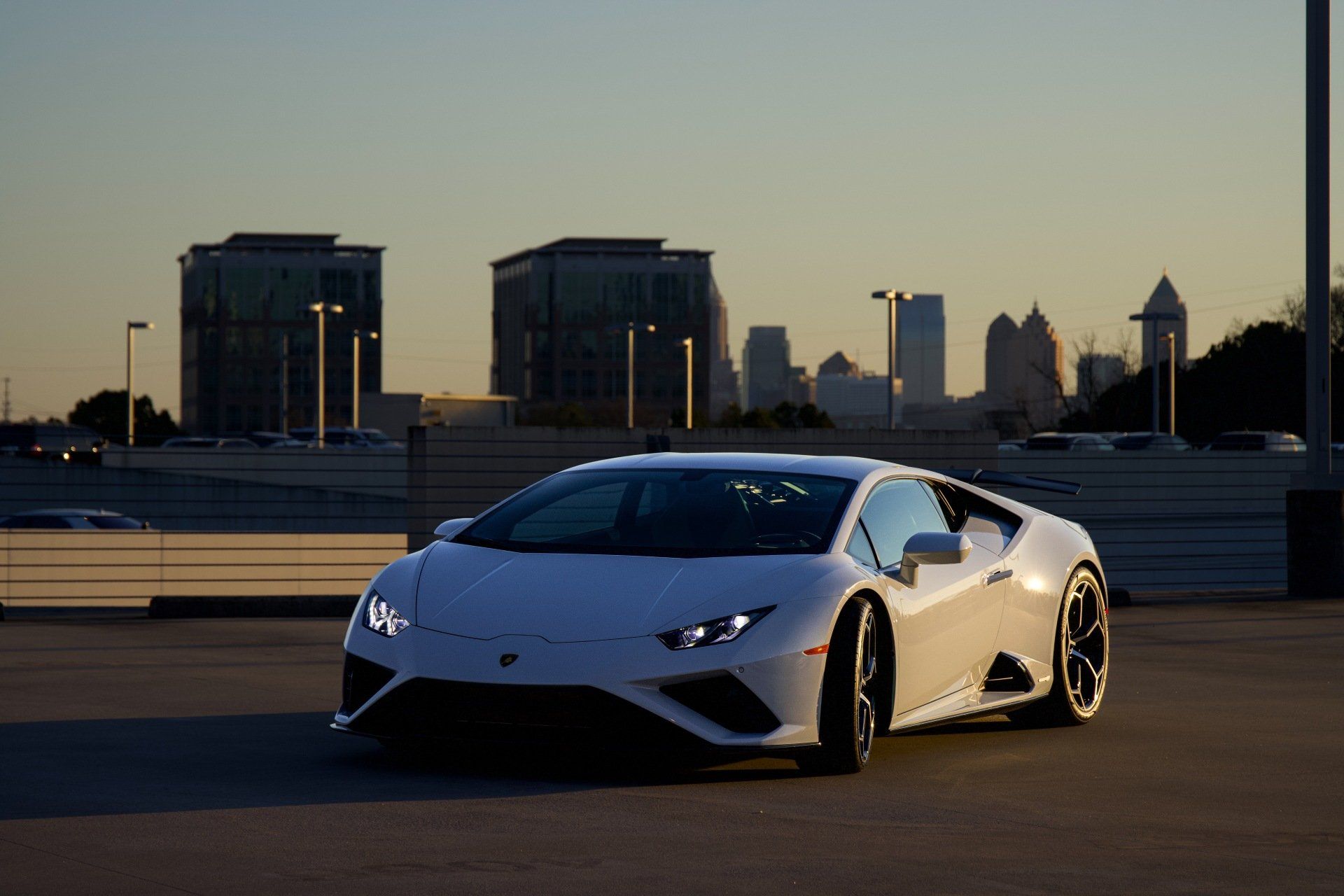 White Lamborghini sports car parked in front of a city skyline at sunset with Xpel paint protection film installed.