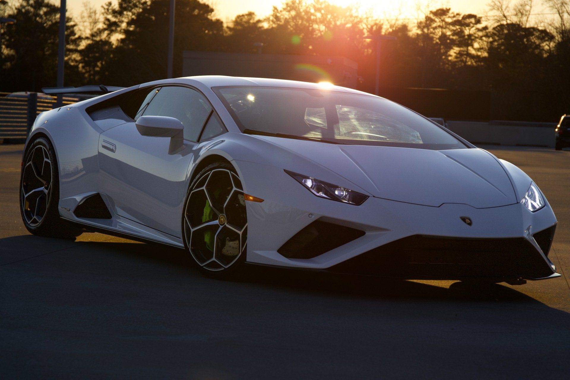 White Lamborghini Huracan parked outside at sunset, with yellow-green brake calipers visible.