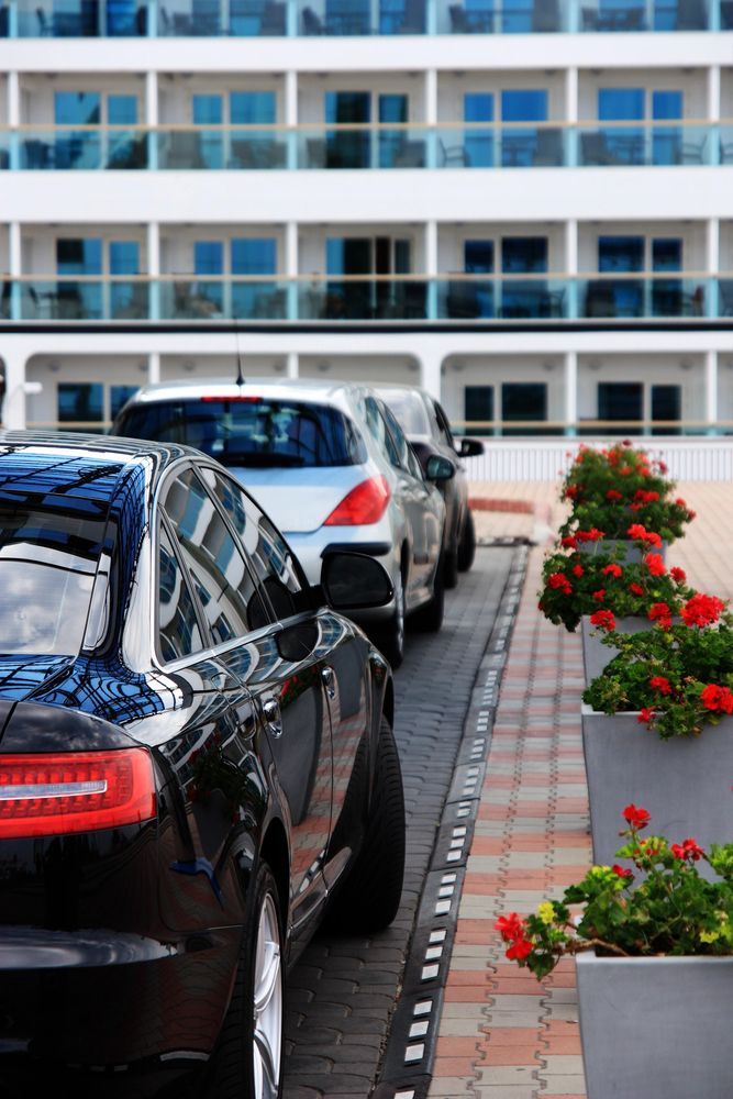 Auto parcheggiate accanto a fioriere di fronte a un moderno condominio.