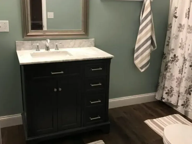 Bathroom vanity with dark cabinet, white sink, mirror, striped towel, and floral shower curtain