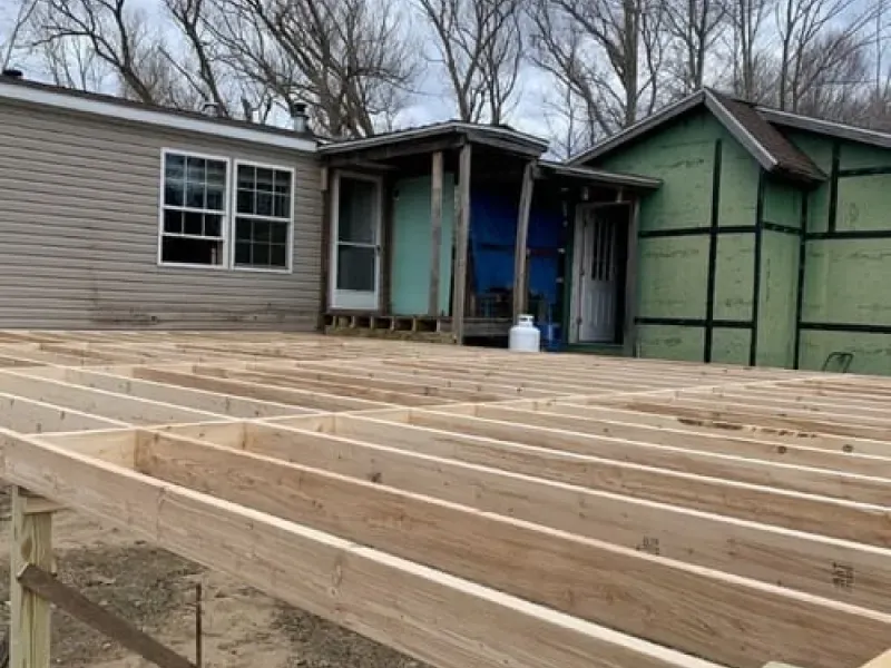 Partially built wooden deck beside a house, with exposed framing in the foreground