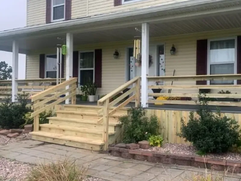 Front porch with new wooden ramp and steps leading to a house entrance