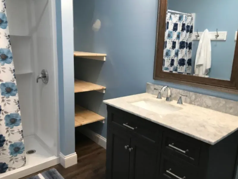 Bathroom with dark vanity, marble countertop, mirror, shower curtain, and built-in corner shelves