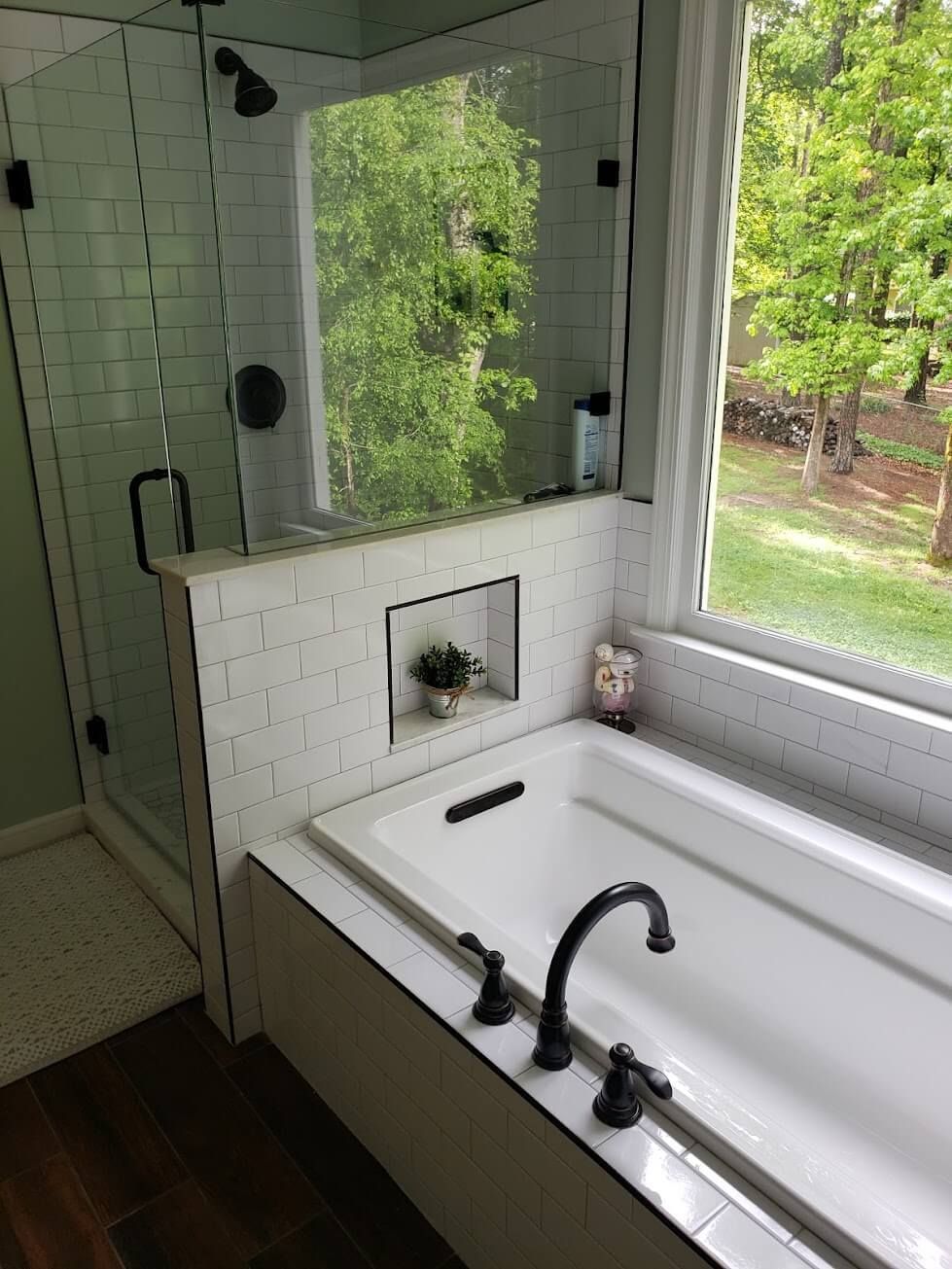 A bathroom with a bathtub , shower , and window.