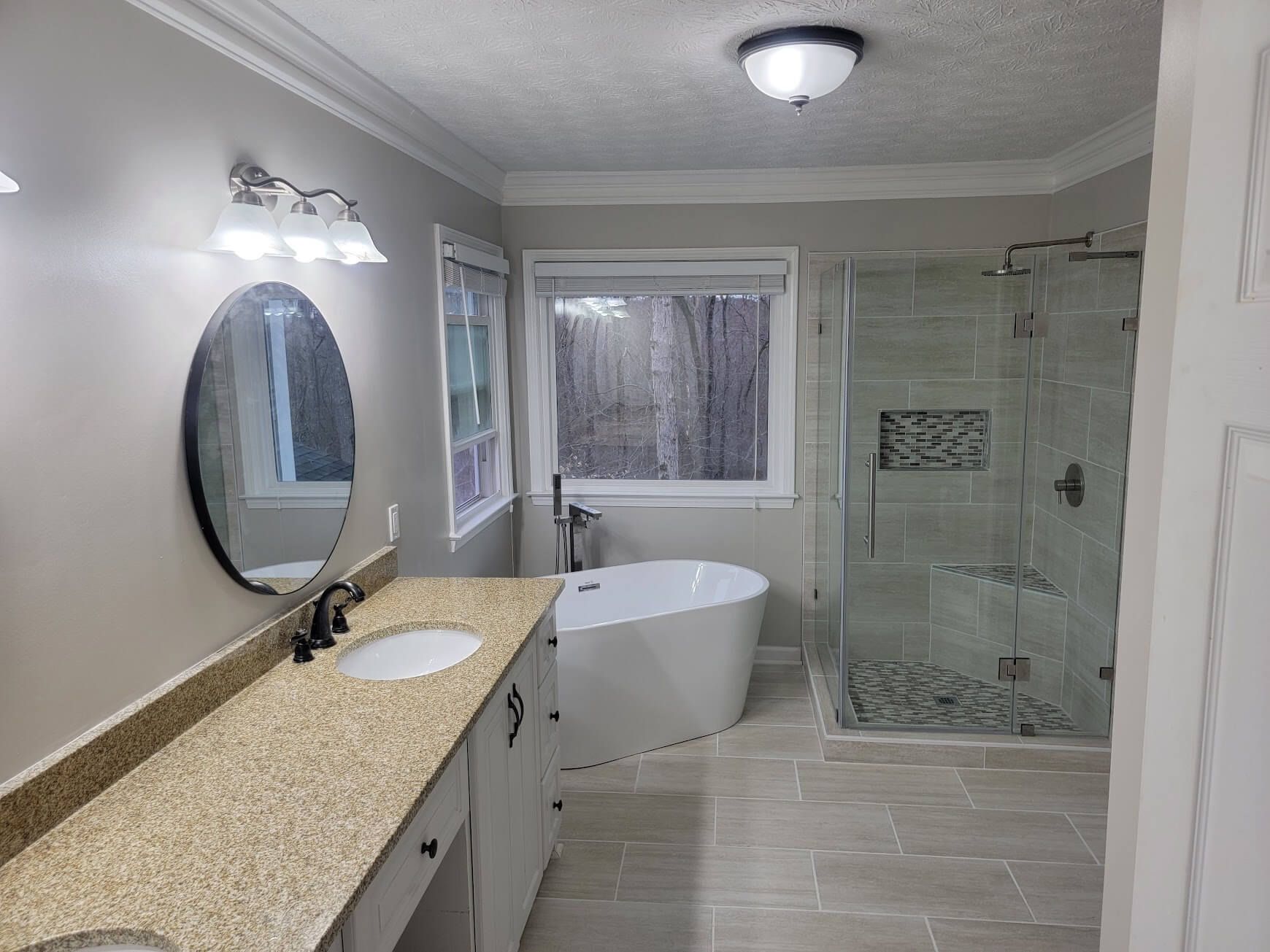A bathroom with a tub , sink , shower and mirror.