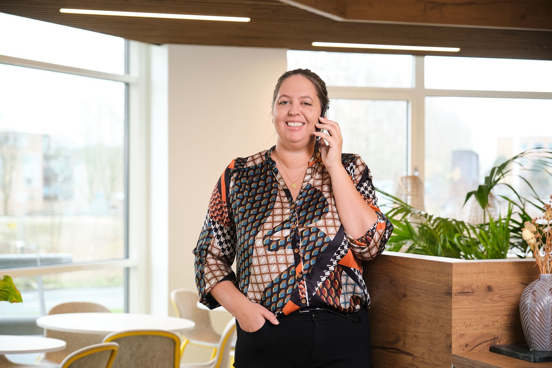 Een vrouw staat in een kamer en belt via een mobiele telefoon.