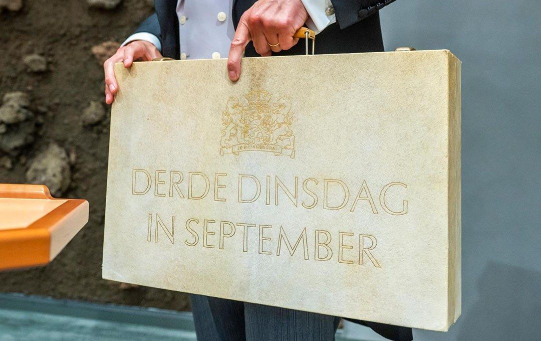 Person holding a beige stone plaque with engraved text outdoors, near a stone wall