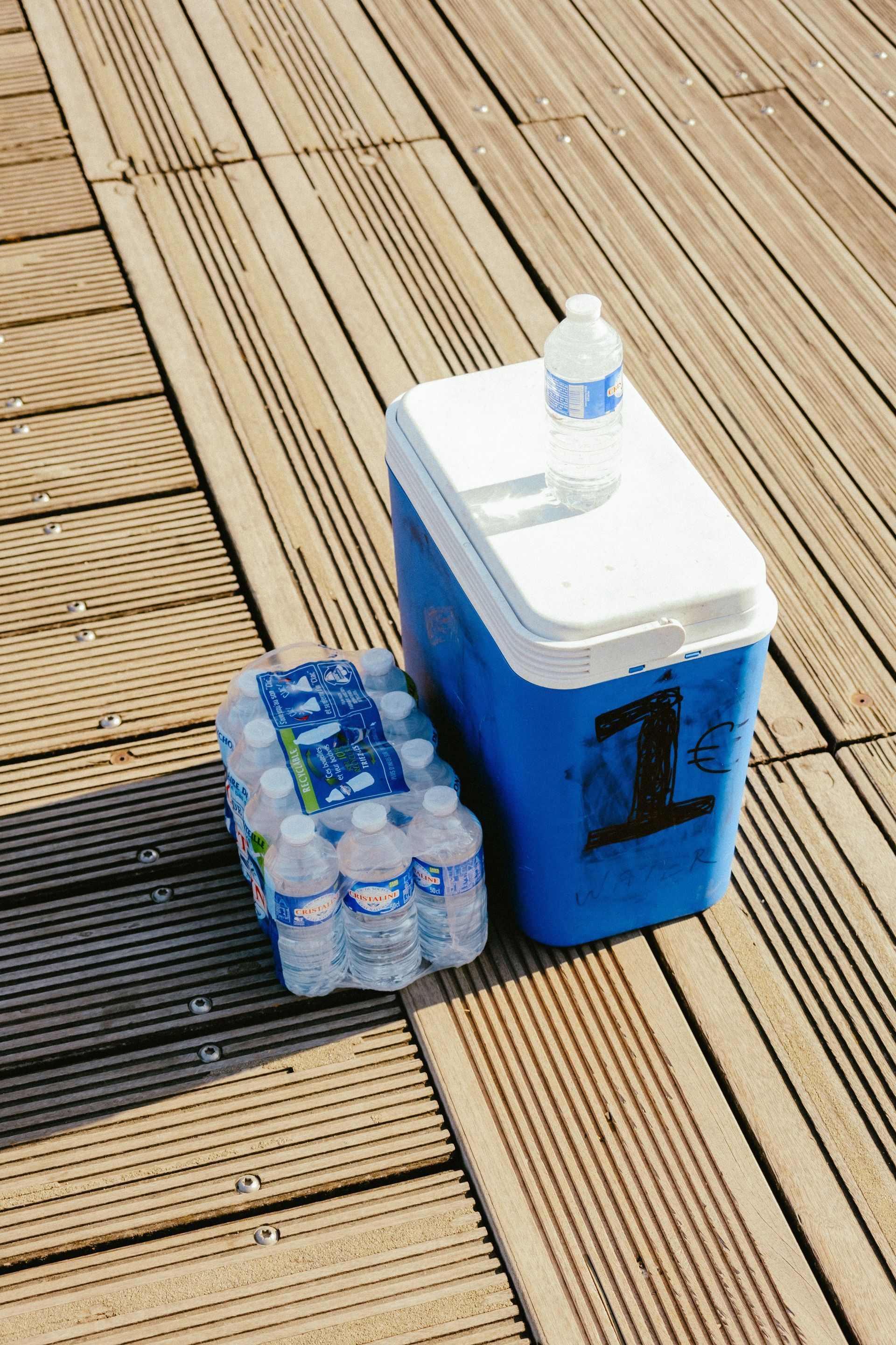 Blue cooler and bottled water on a wooden deck.