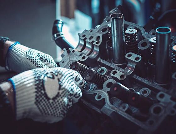 A person wearing gloves is working on a car engine.