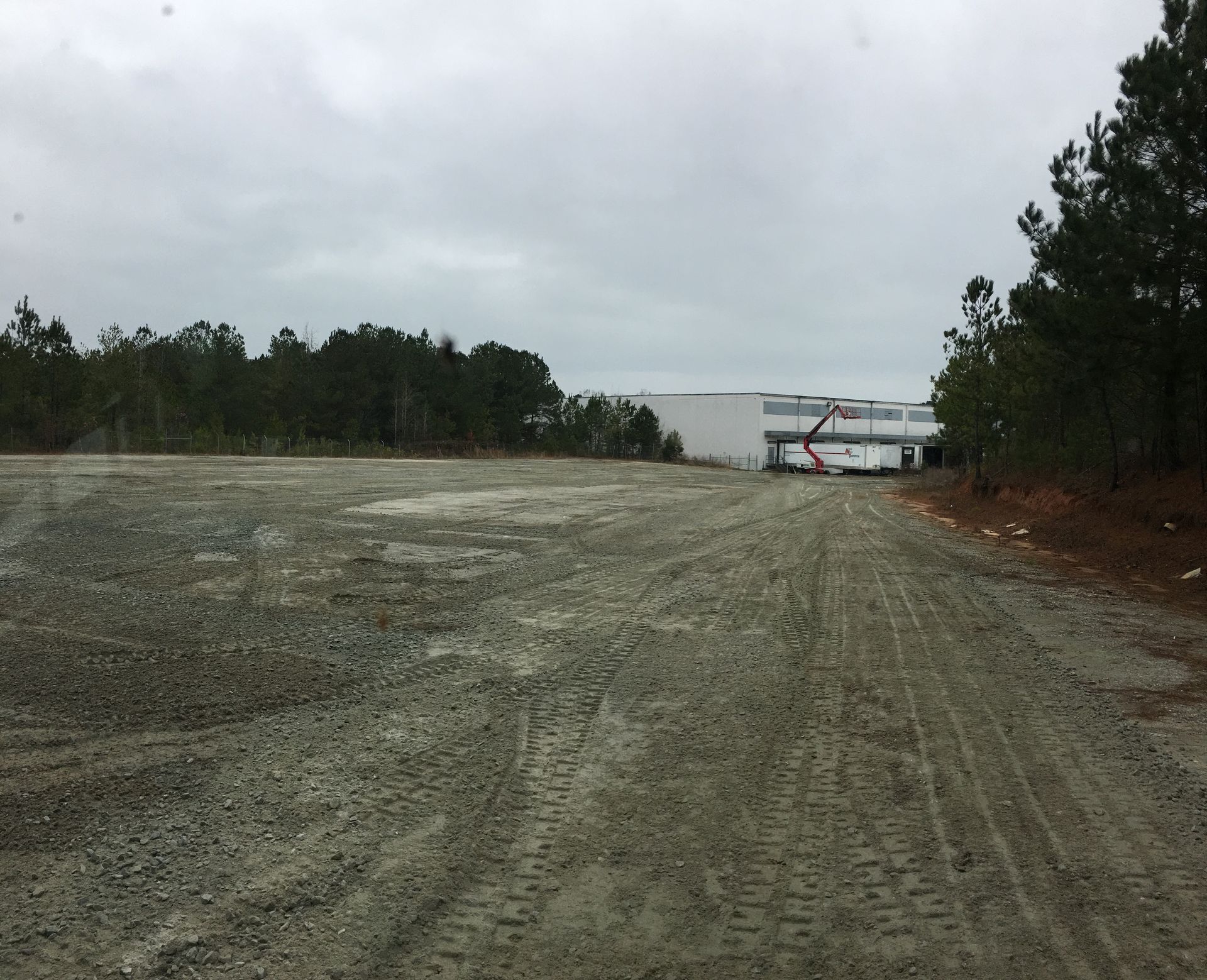 A dirt road with a white building in the background