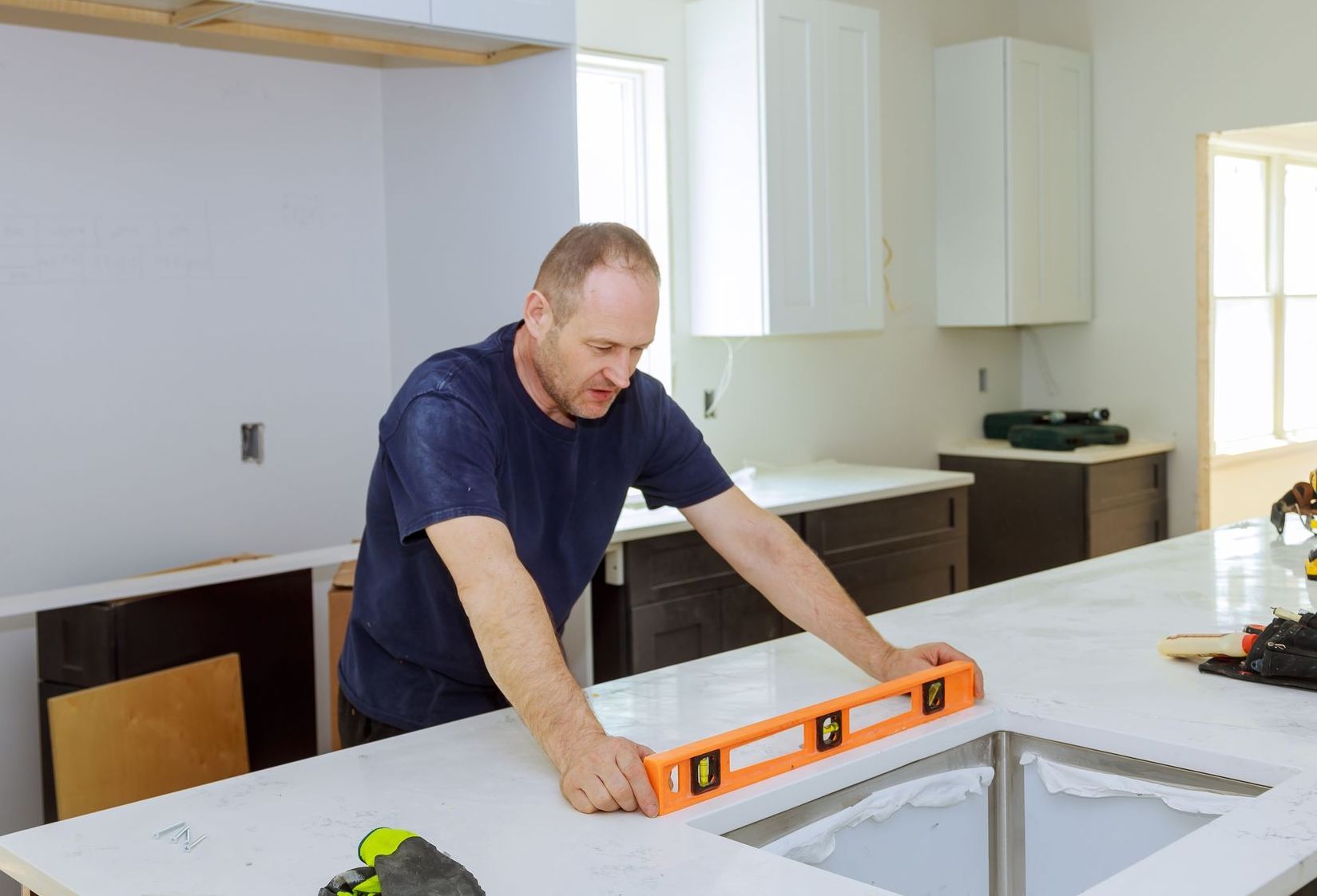 Man using a level on a kitchen countertop during installation.