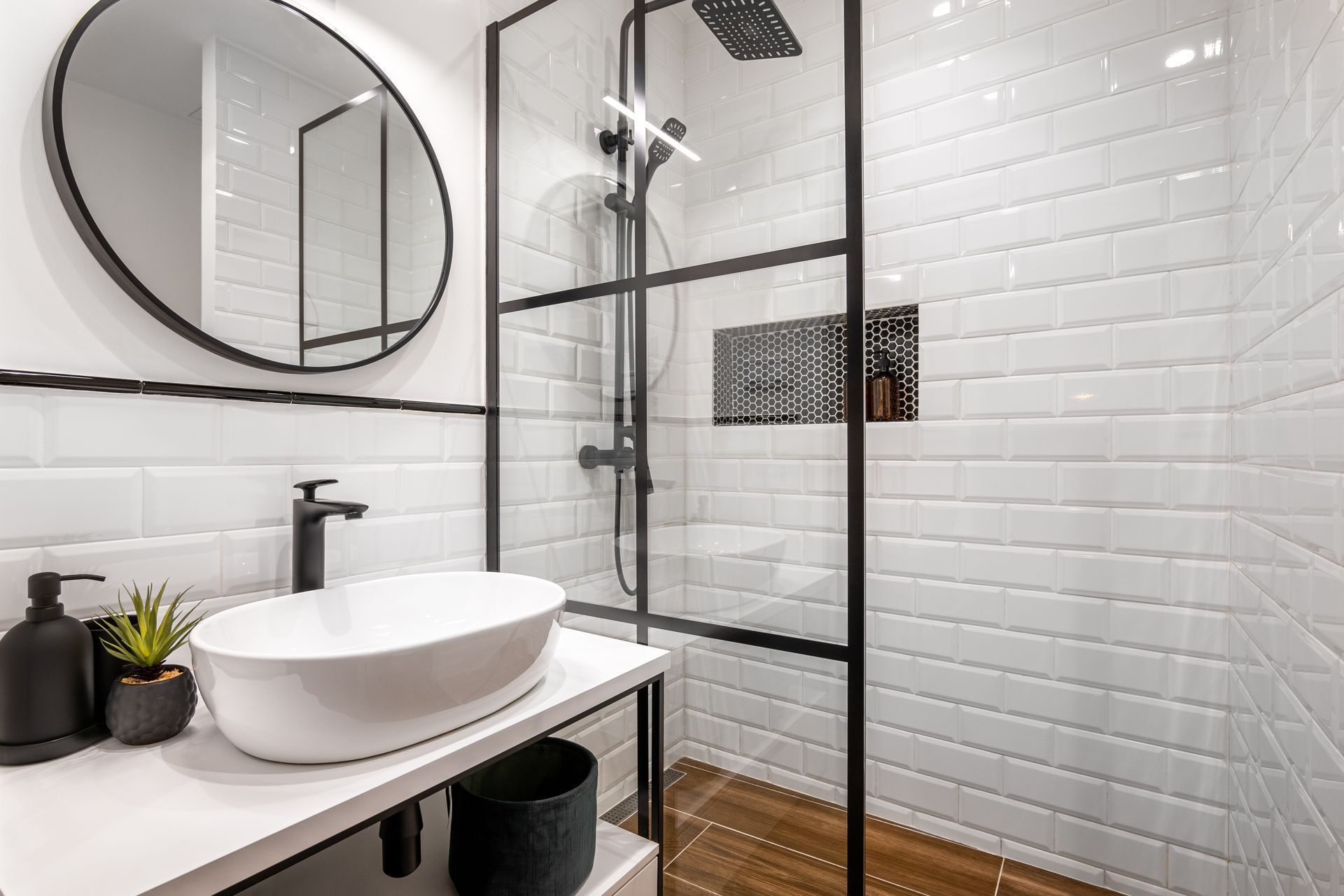 Modern bathroom with white subway tile, black fixtures, and a glass shower enclosure.
