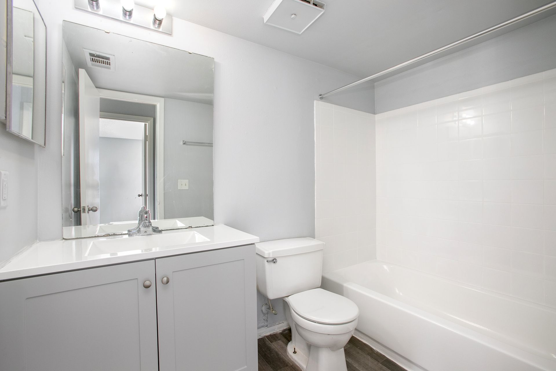 Bright bathroom with white vanity, mirror, toilet, and shower/tub combo