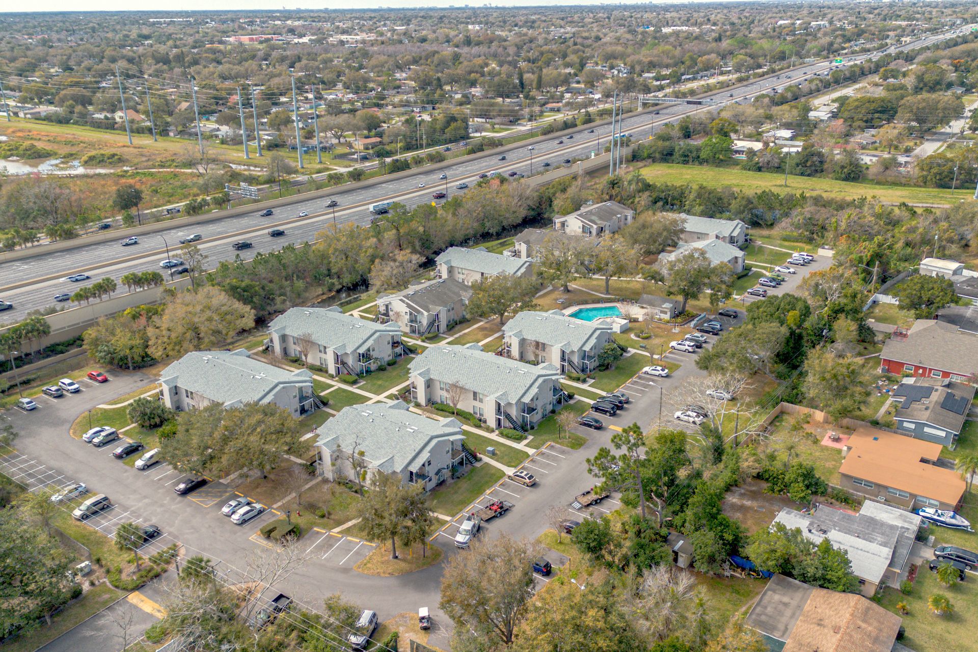 Aerial view of apartment buildings, parking lots, and a highway in a suburban neighborhood