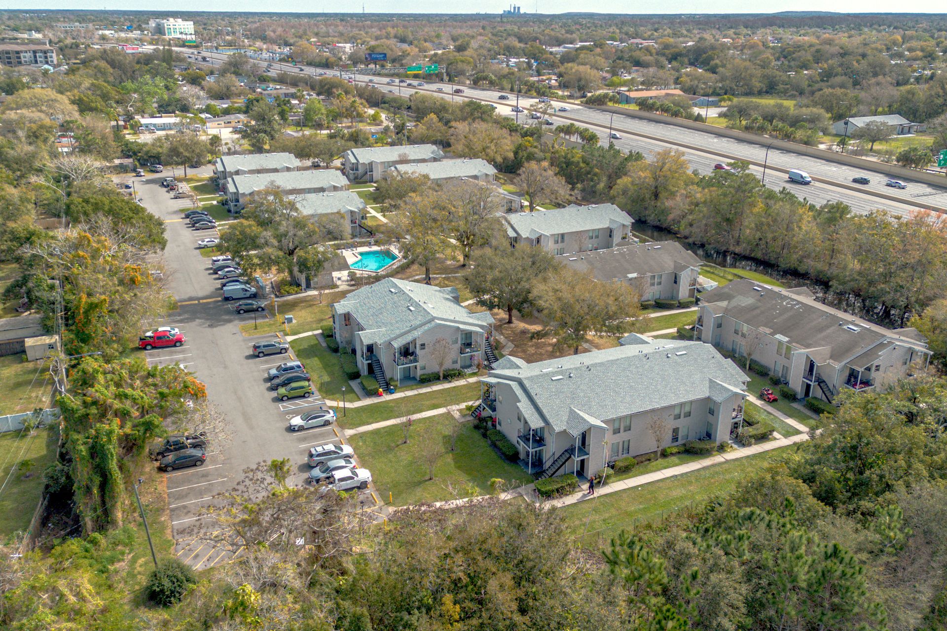 Aerial view of apartment buildings, parking lots, and trees in a suburban neighborhood