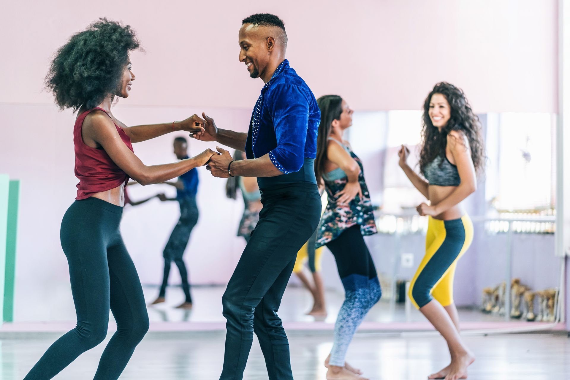 Persone che ballano la salsa in una sala da ballo, sorridenti.