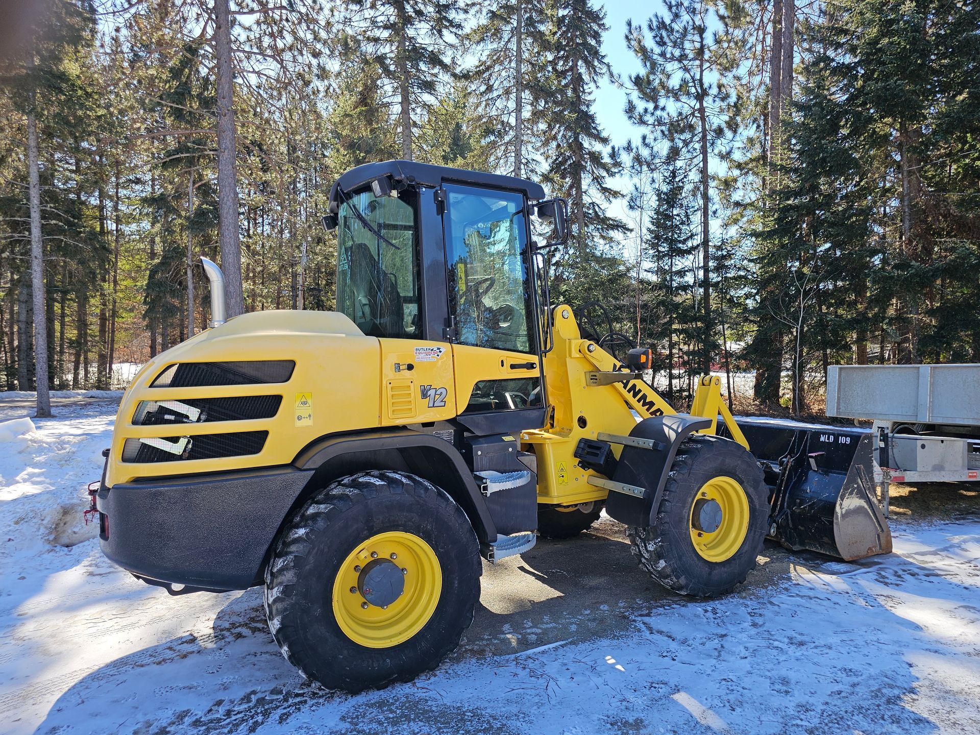 A yellow and black tractor is parked in the snow.