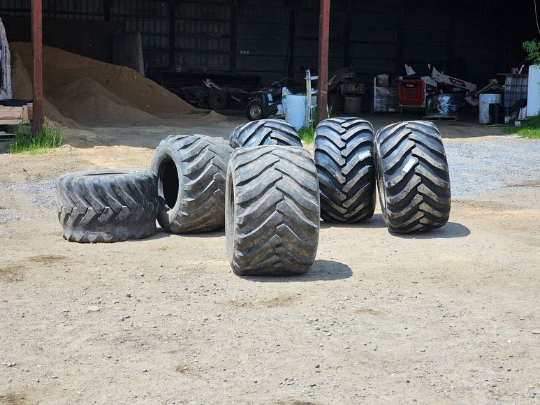 A bunch of tires are sitting on the ground in front of a building.