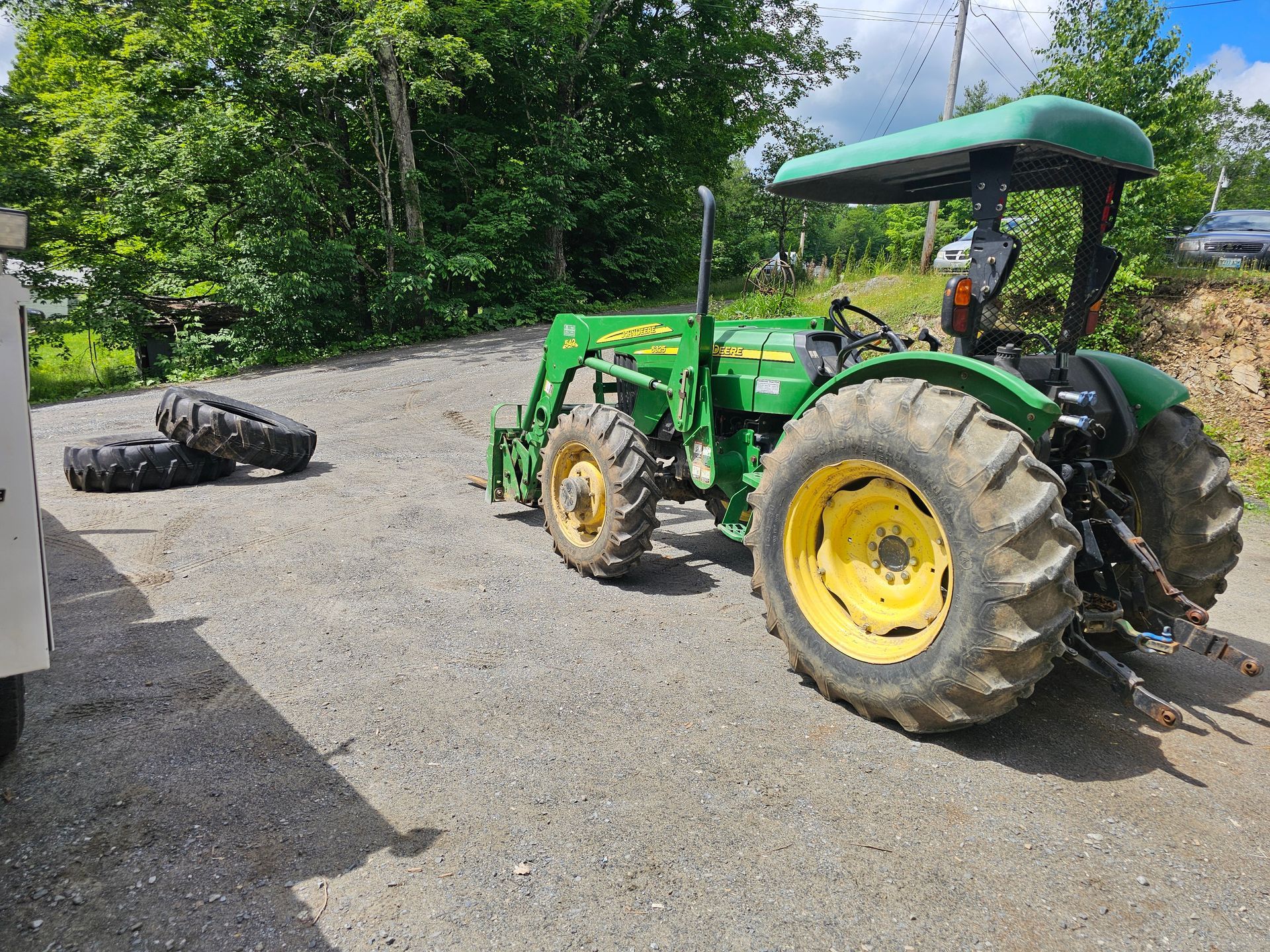 A green and yellow tractor is parked on the side of the road.