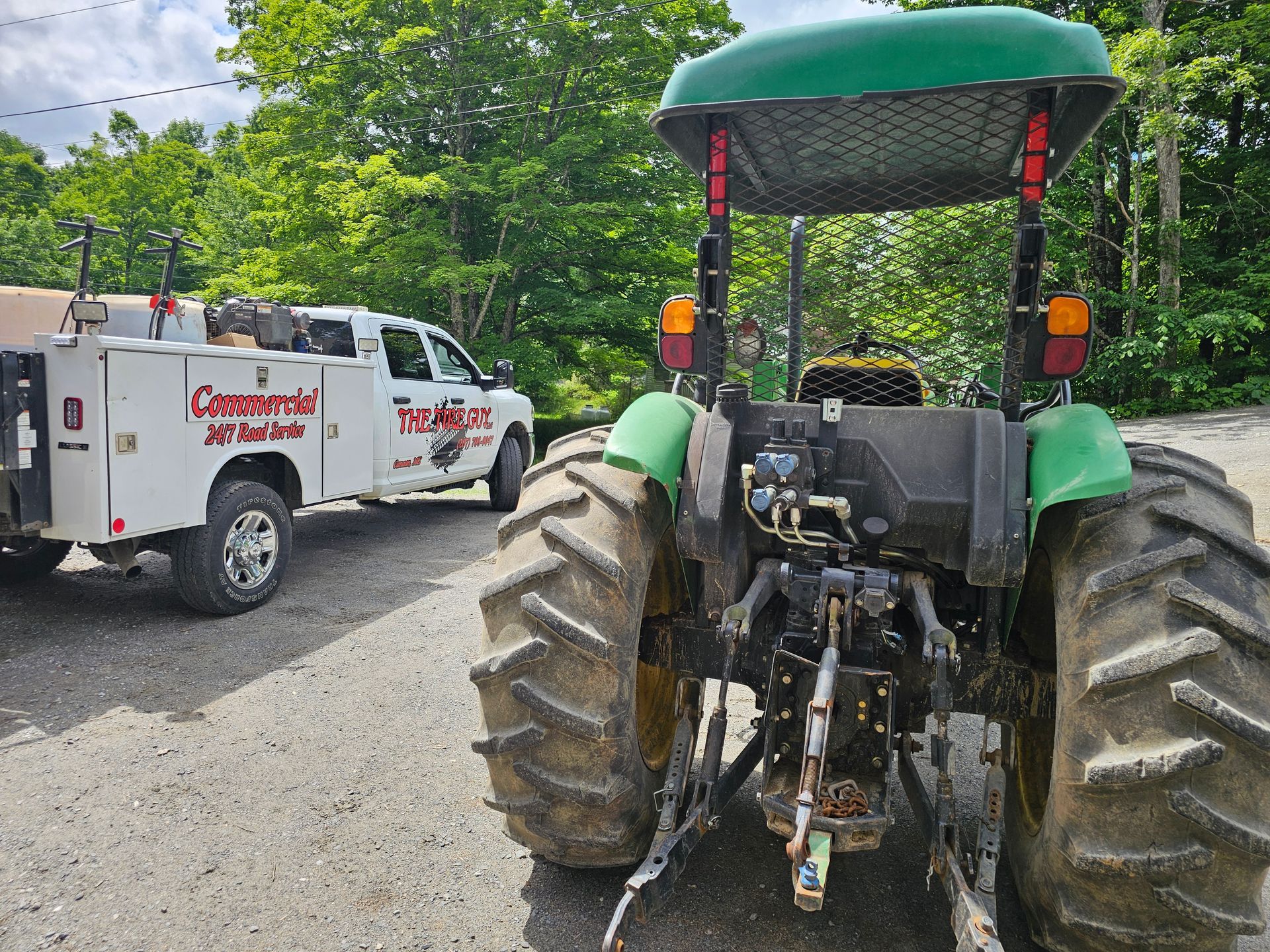 A green tractor is parked next to a white truck.