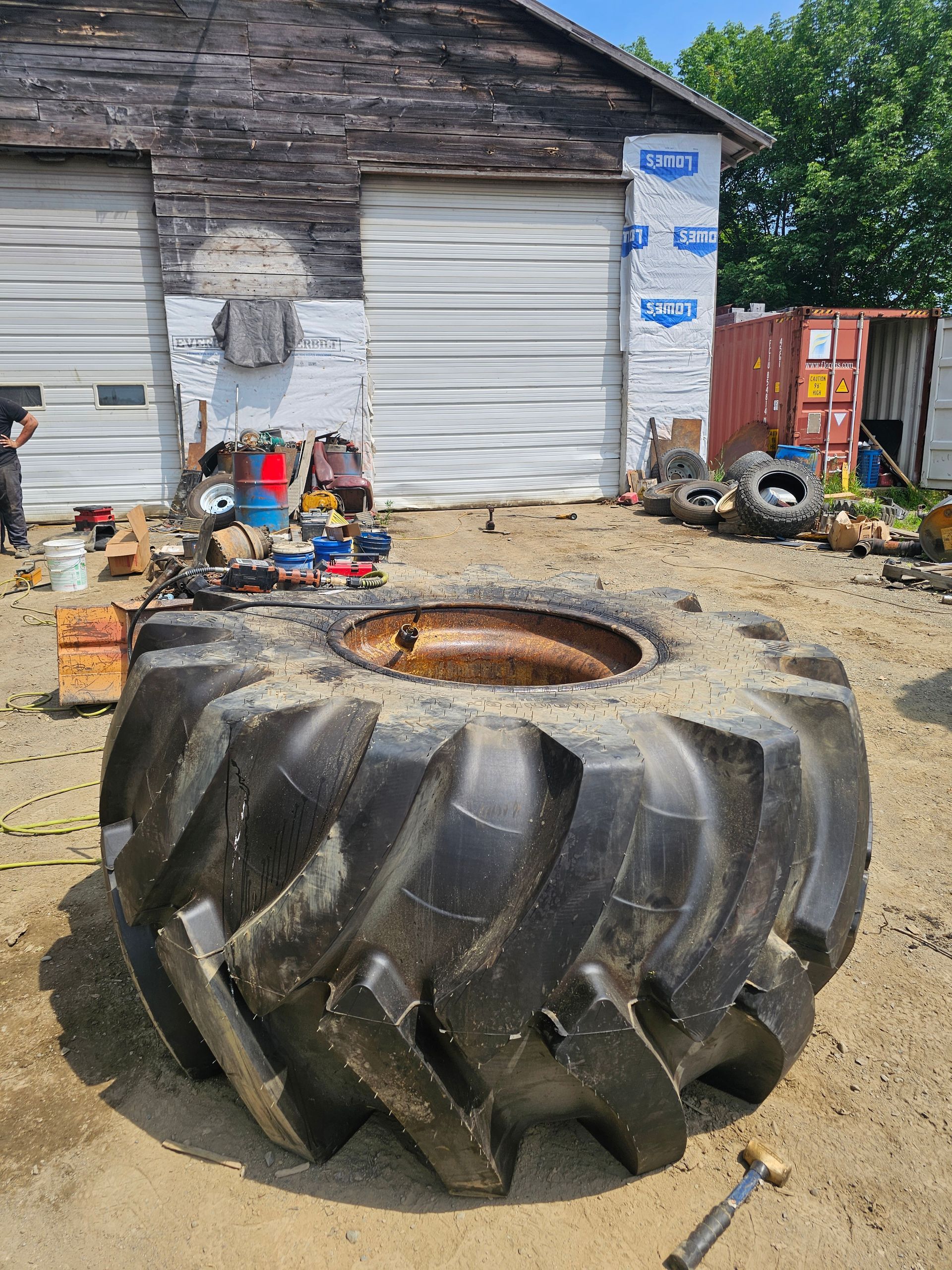 A large tire is sitting in the dirt in front of a building.