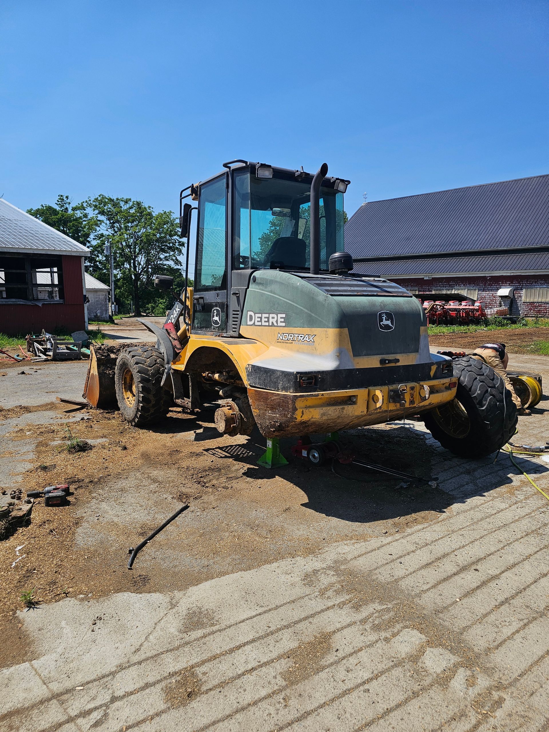 A yellow and green tractor is parked in a dirt field.