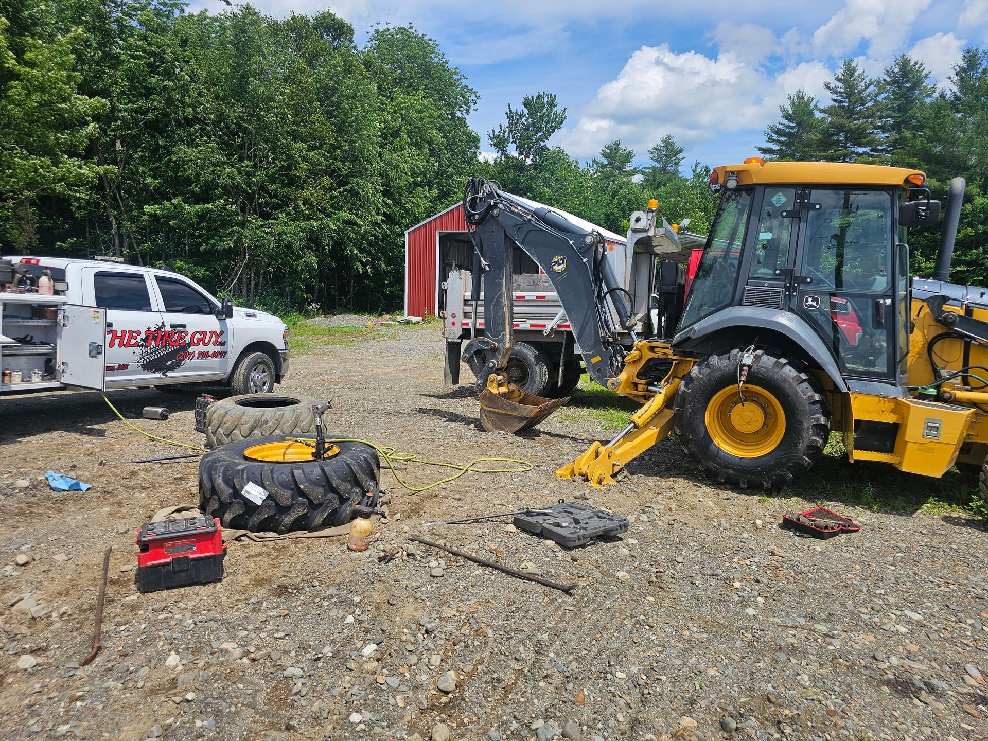 A truck and a tractor are parked in a gravel lot.