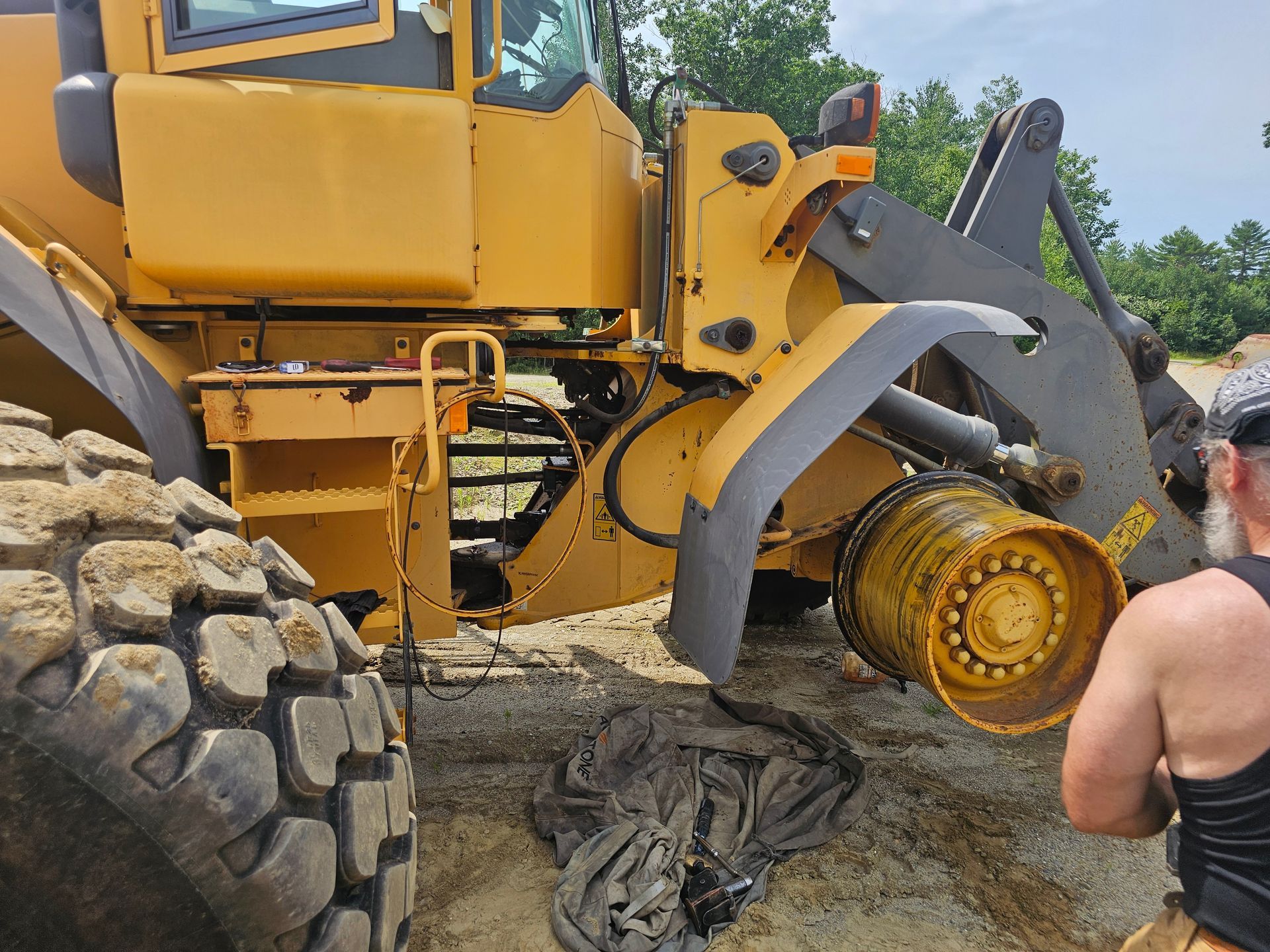 A man is standing next to a large yellow tractor.