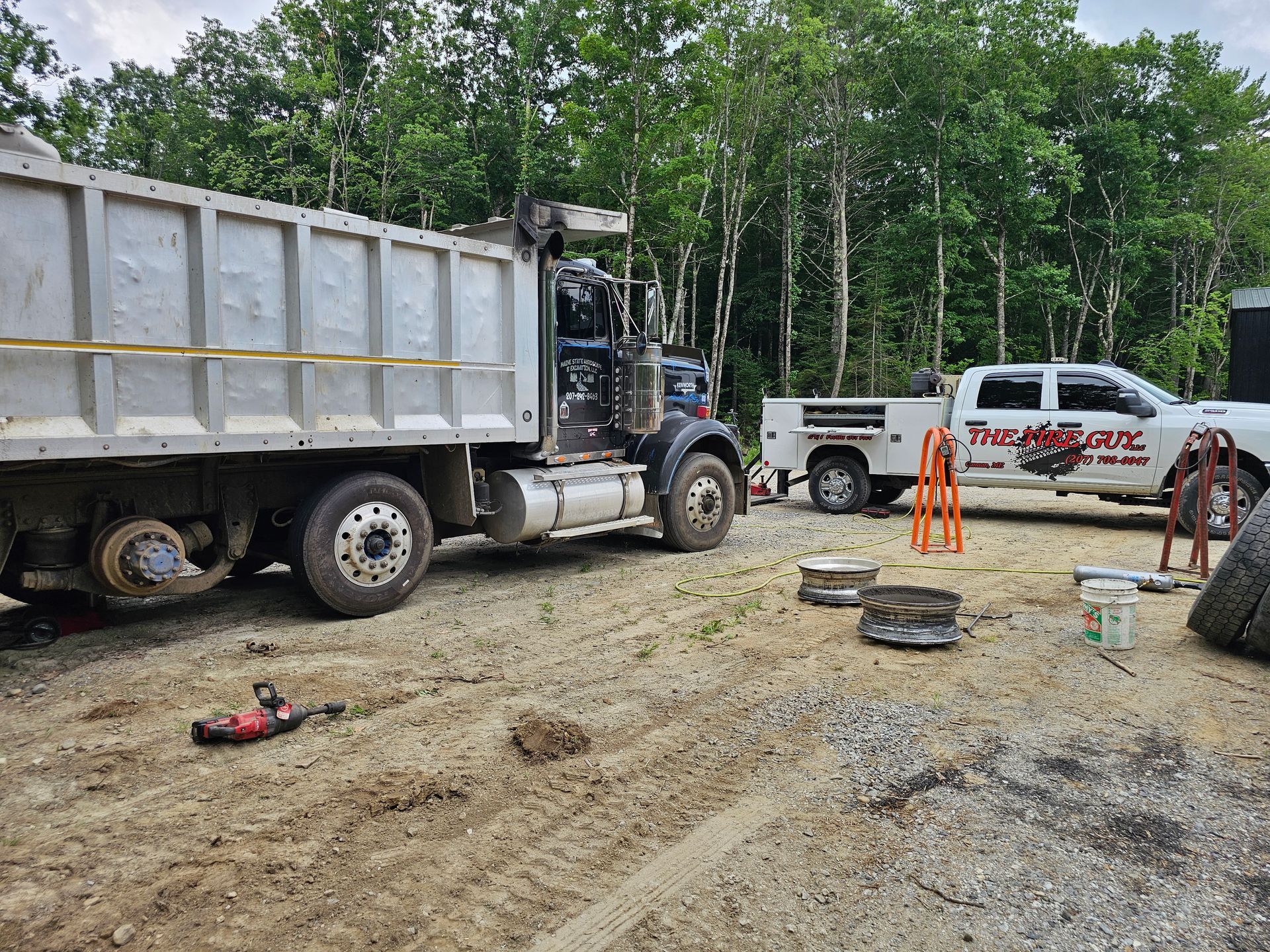 A dump truck and a truck are parked in a dirt lot.