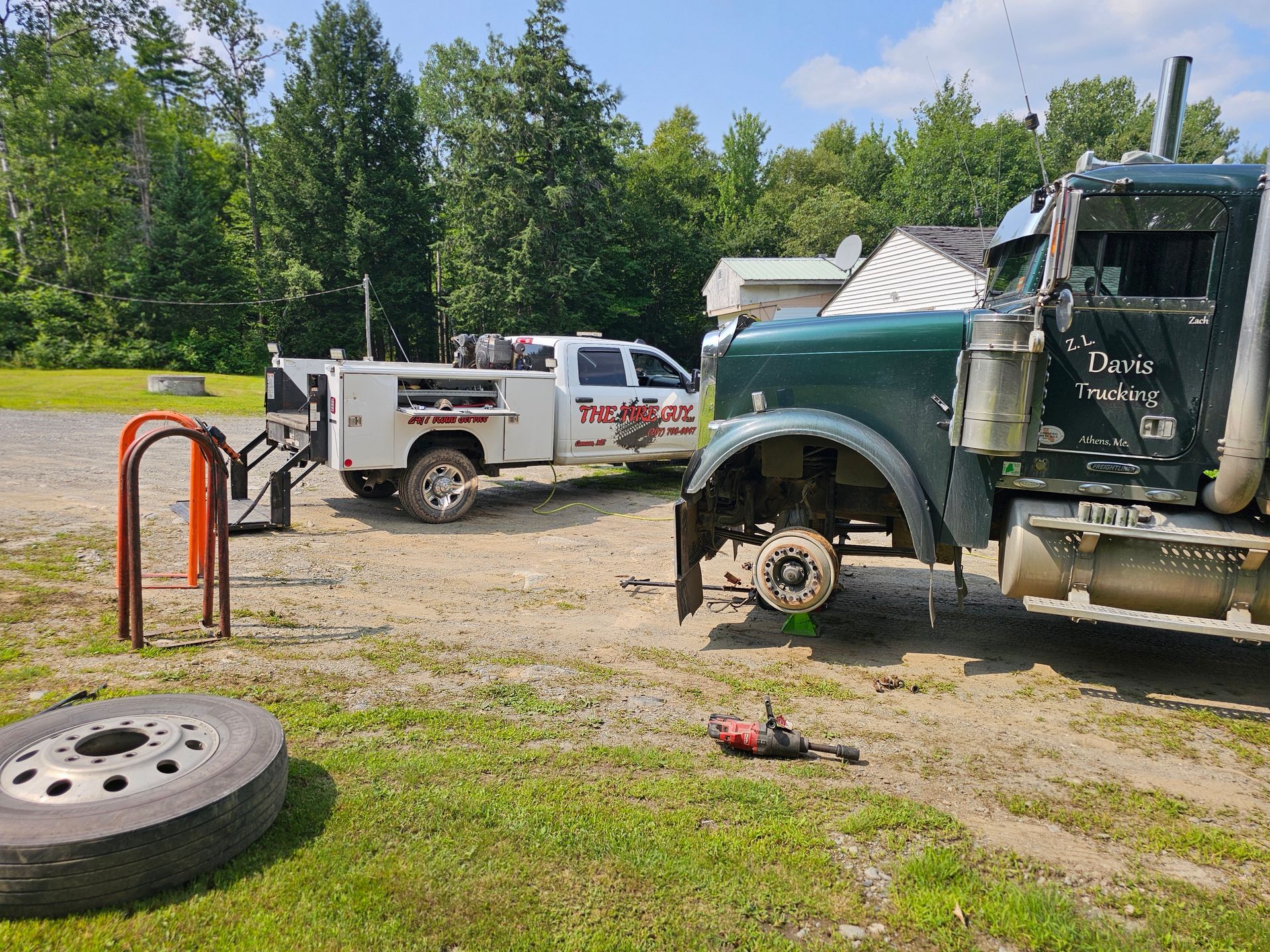 A truck is sitting in the dirt next to a white truck.