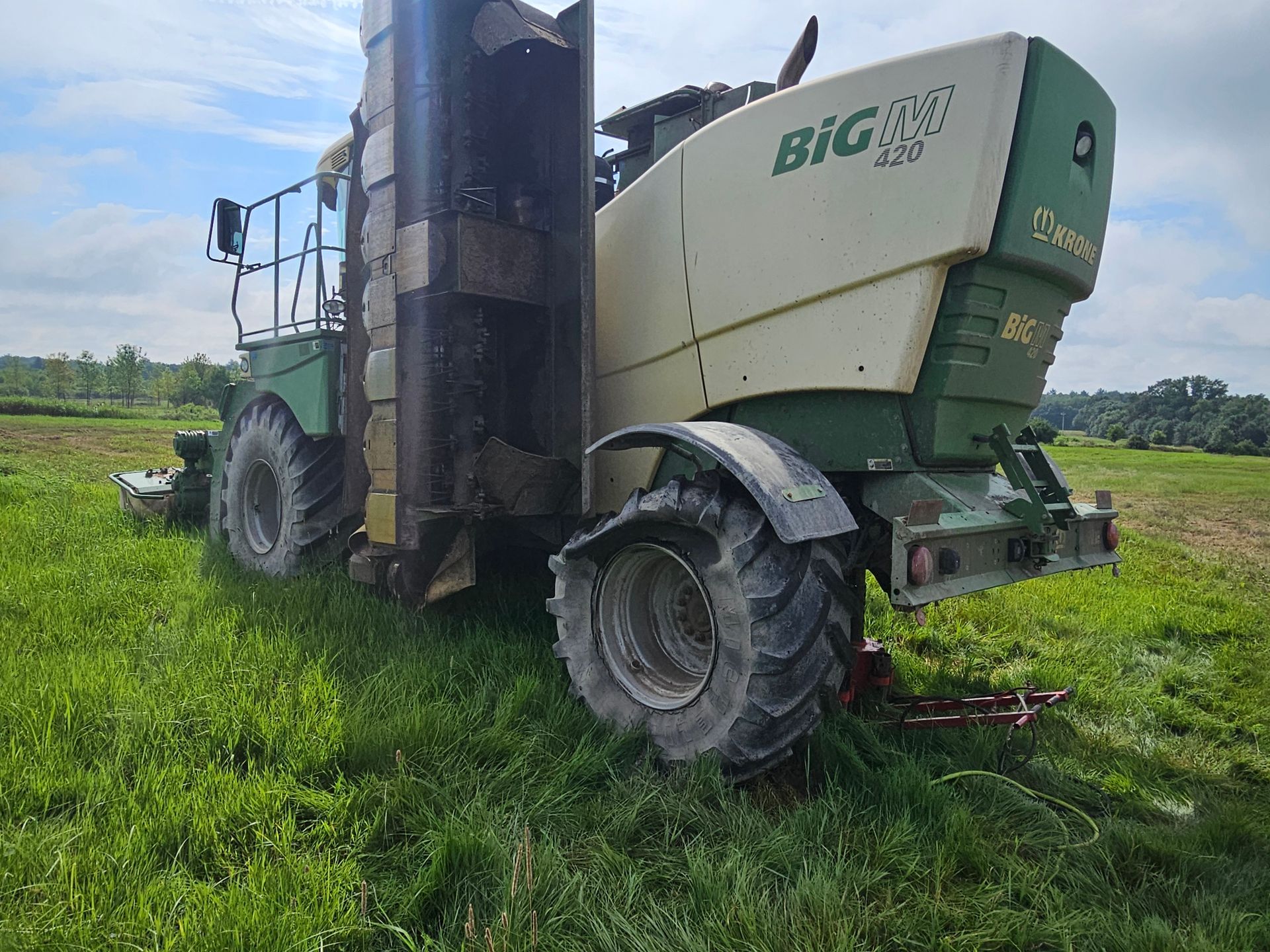 A green and white tractor is parked in a grassy field.