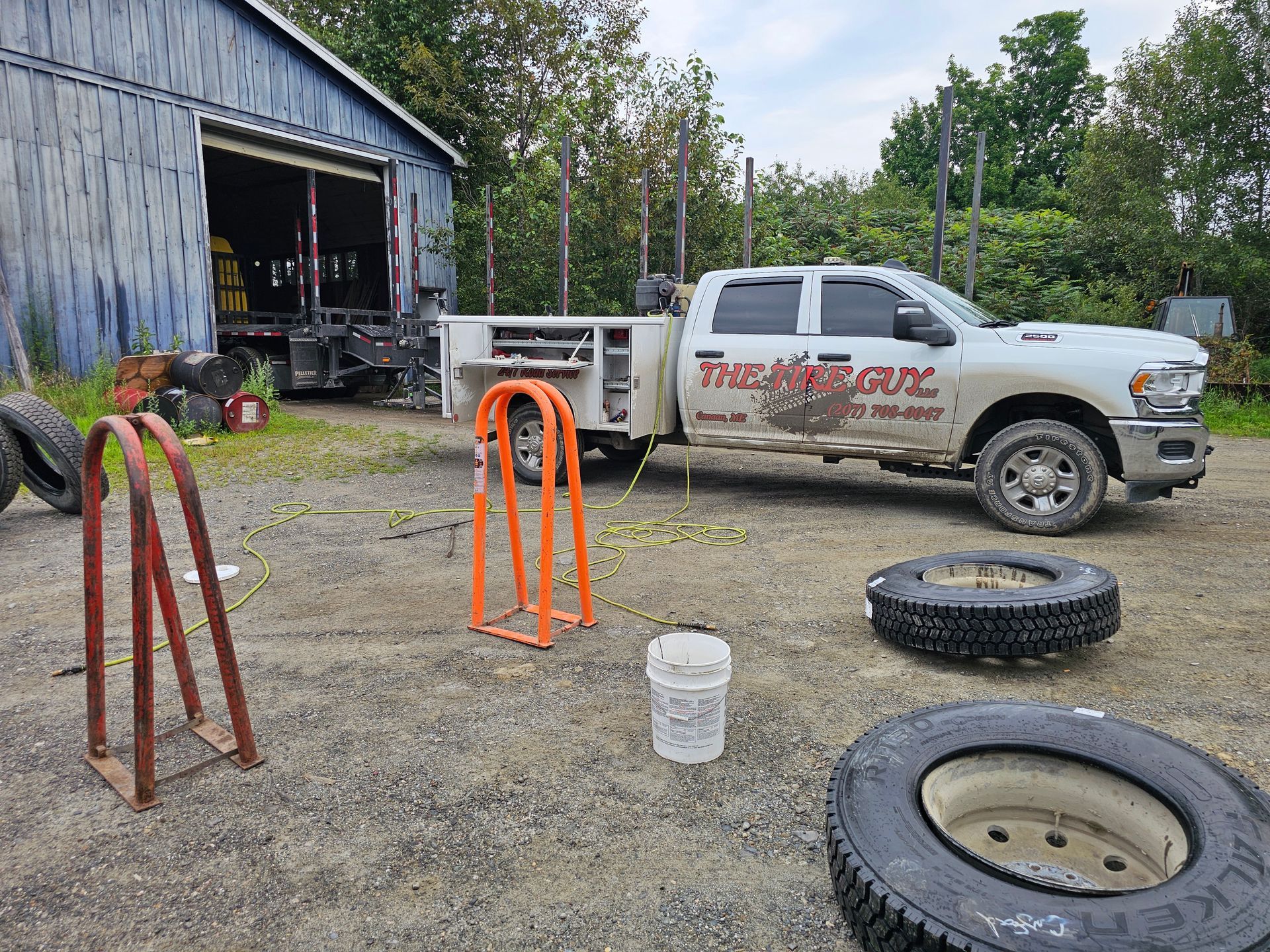 A white truck is parked in a dirt lot next to a shed.