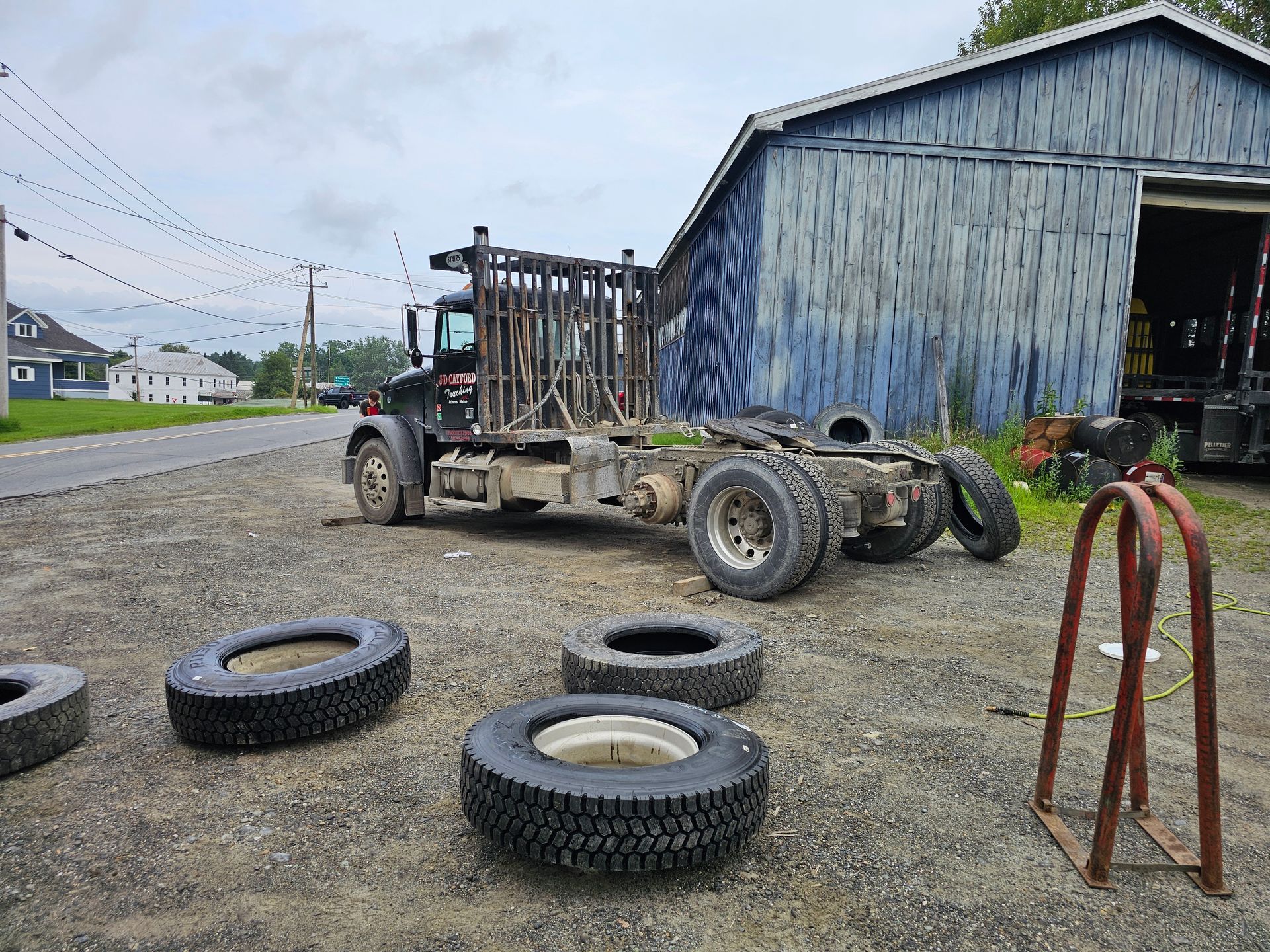 A truck is parked in front of a blue building surrounded by tires.