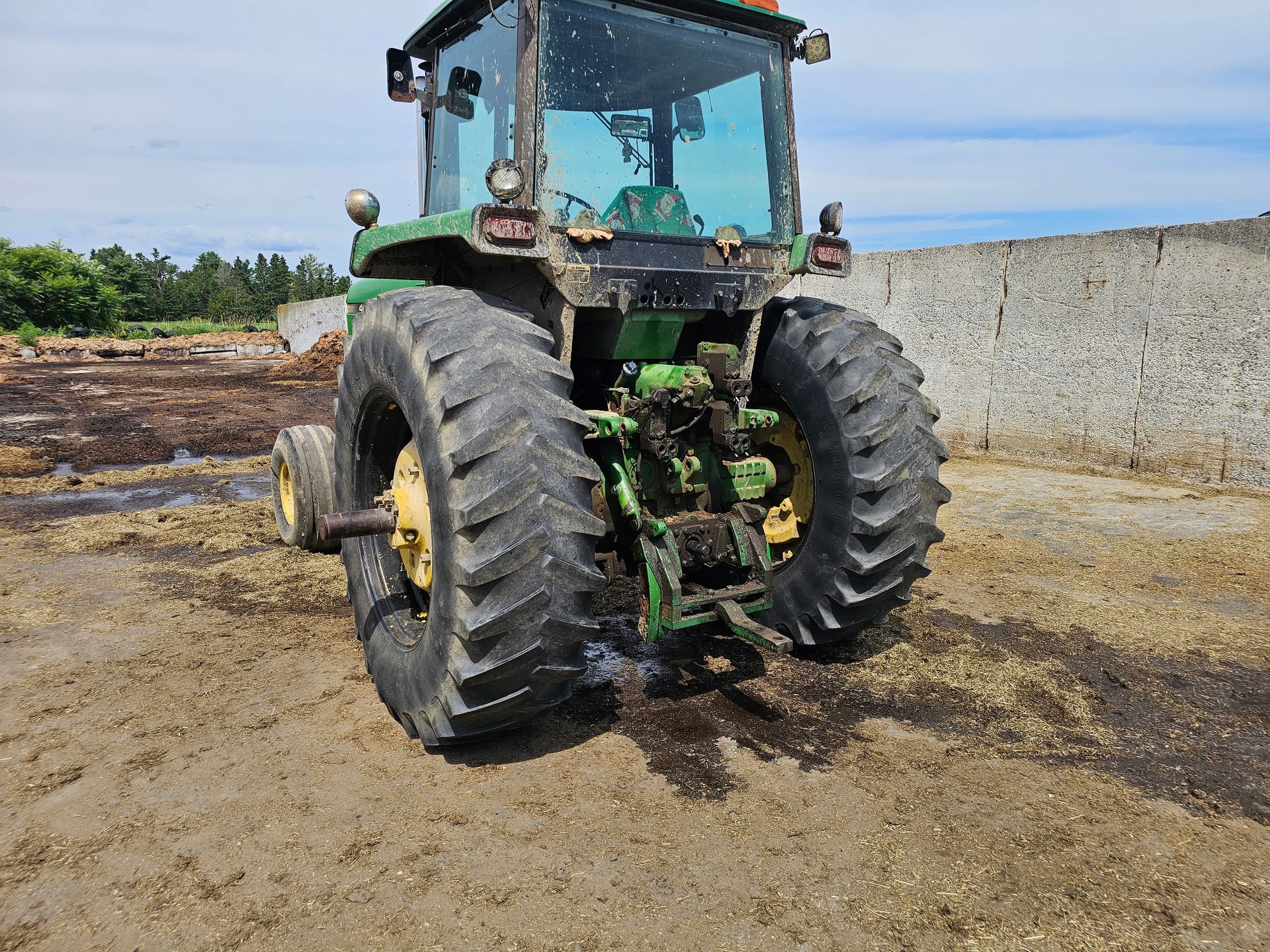 A green john deere tractor is parked in a dirt field.