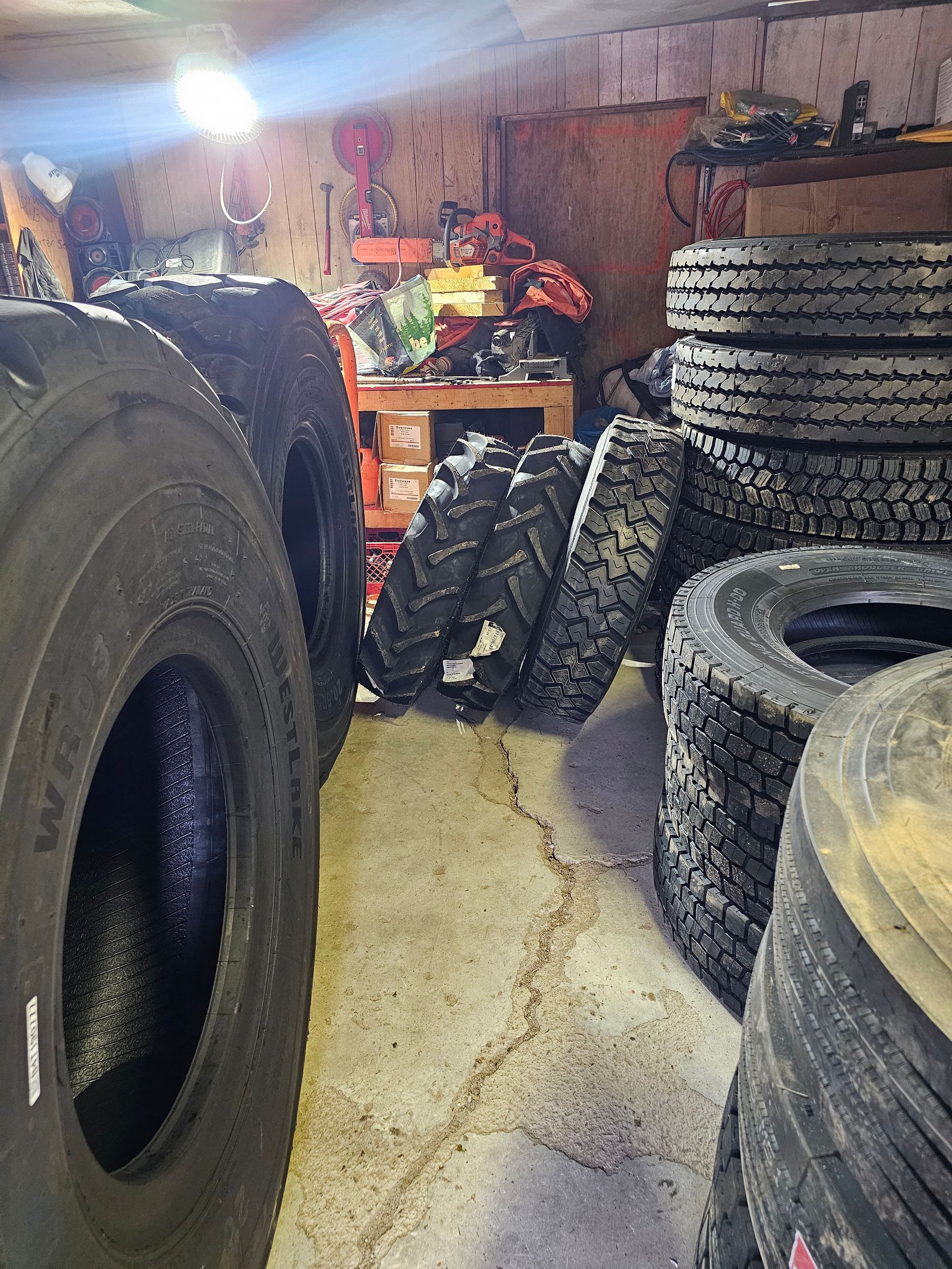 A bunch of tires are stacked on top of each other in a garage.