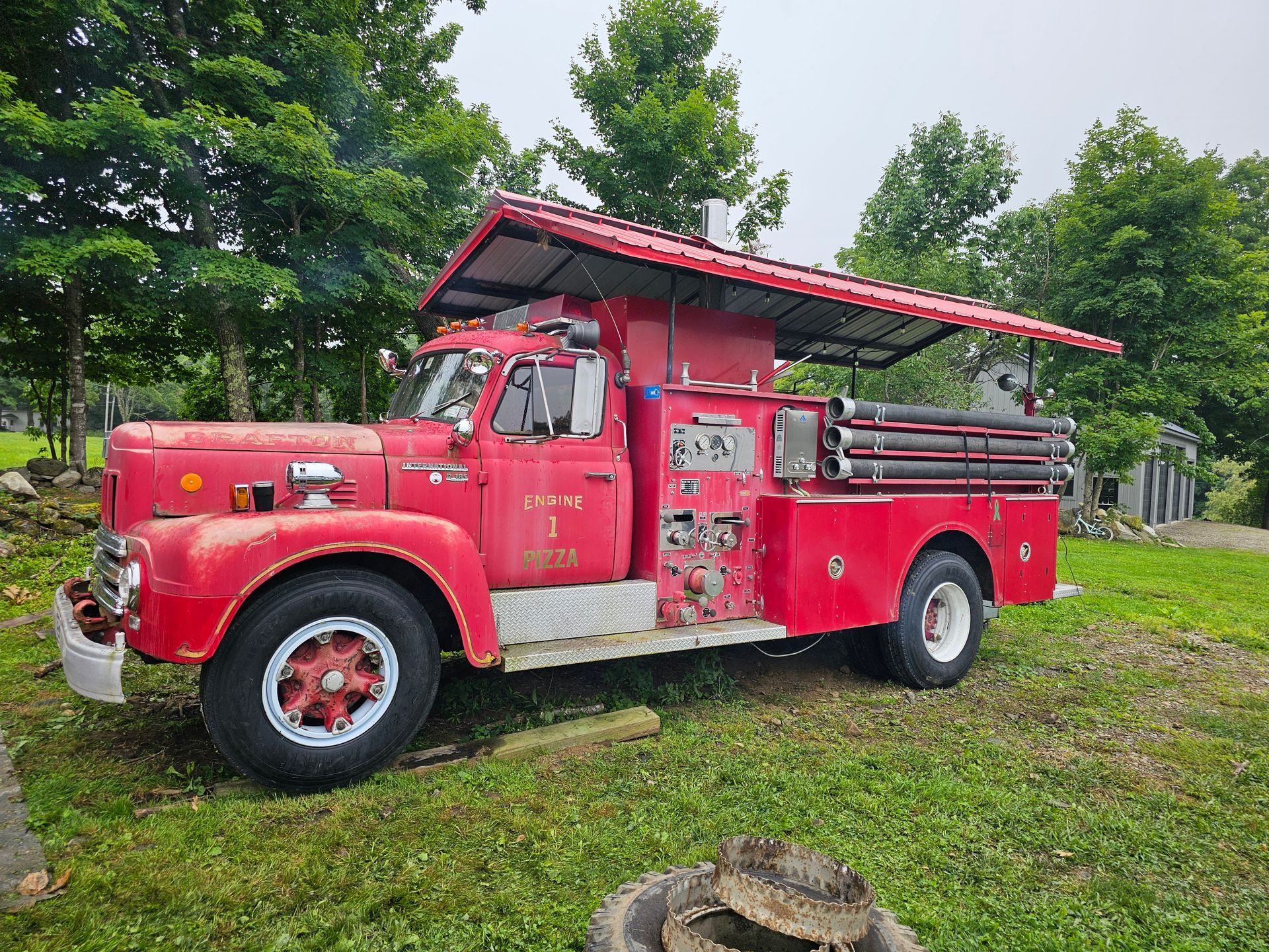 An old red fire truck with a red roof is parked in a grassy field.