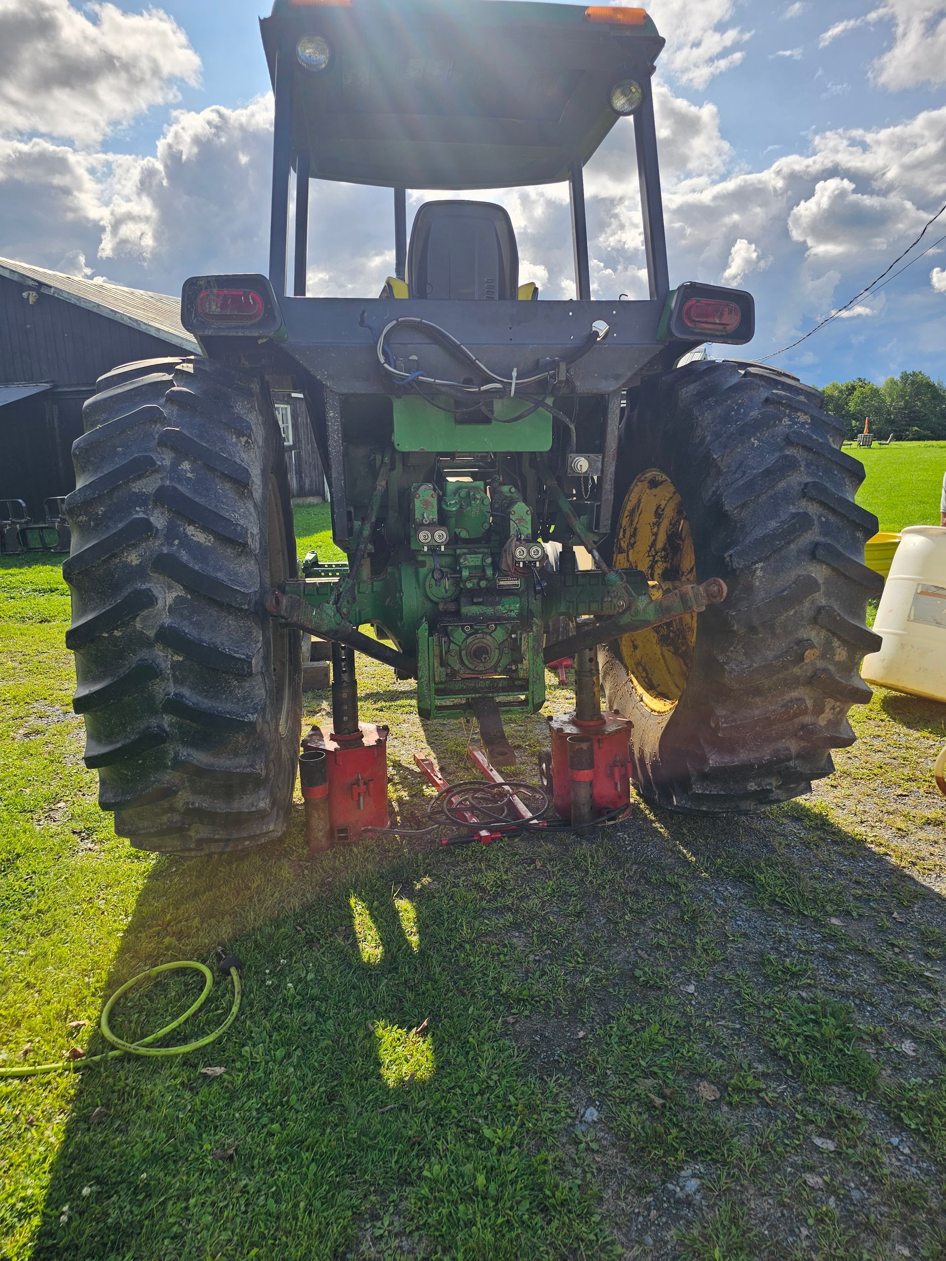 A green and black tractor is parked in a grassy field.