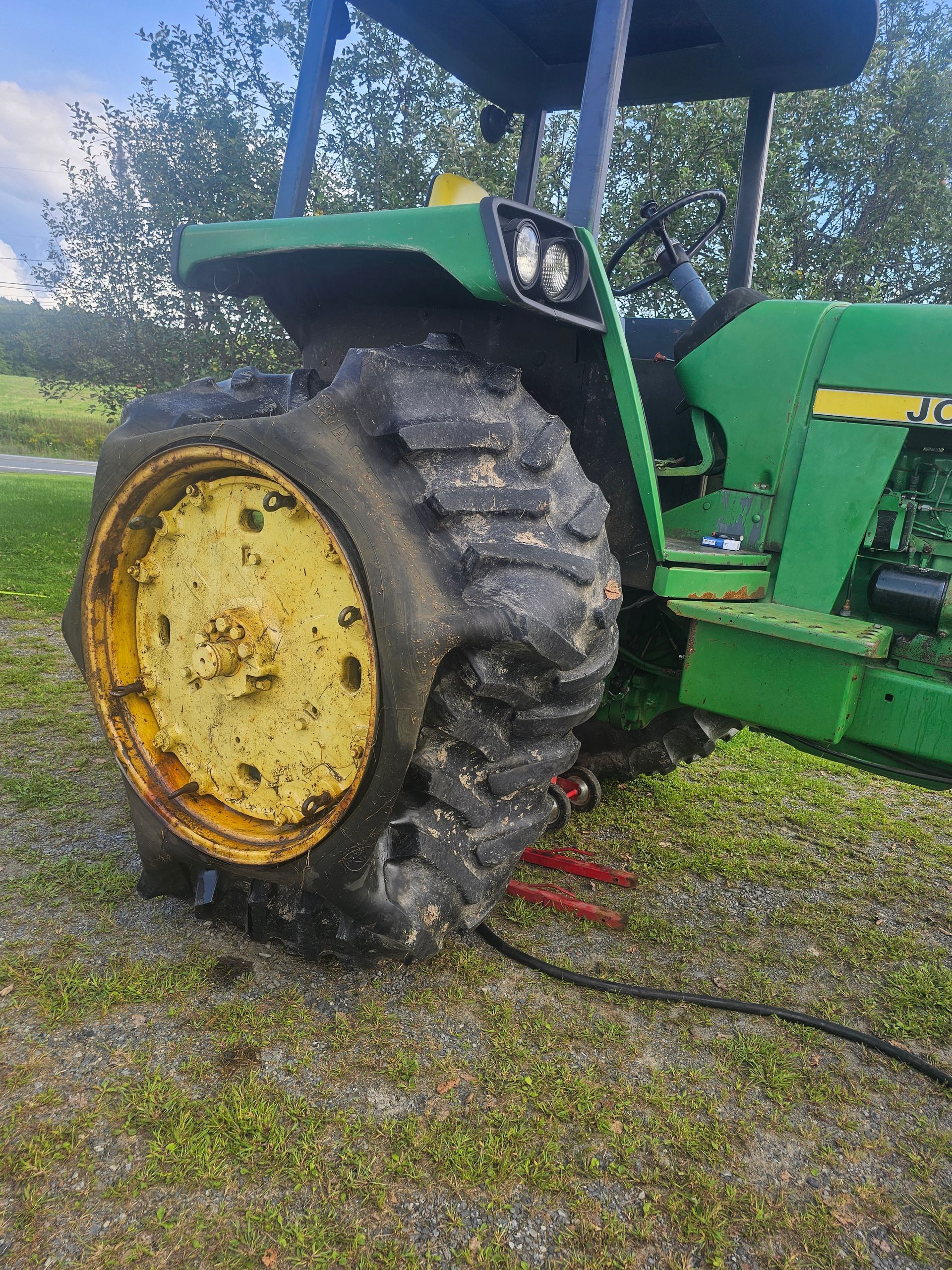 A green john deere tractor with a flat tire