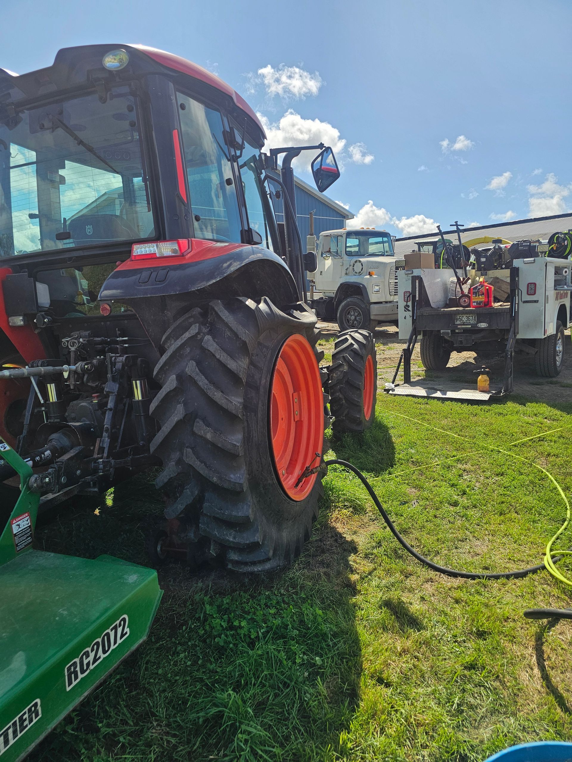 A tractor is parked in a grassy field next to a utility truck.