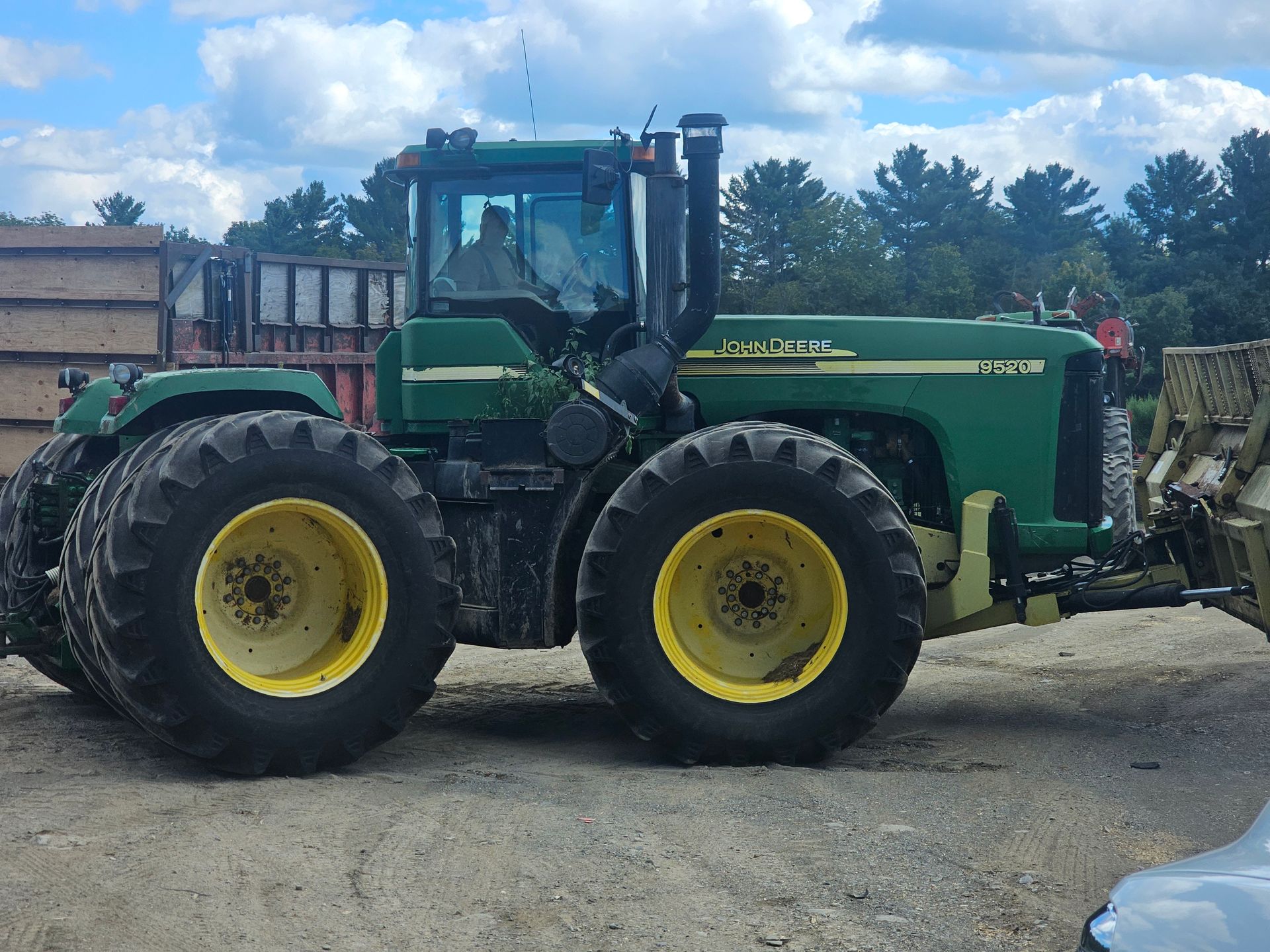A green john deere tractor is parked in a dirt lot