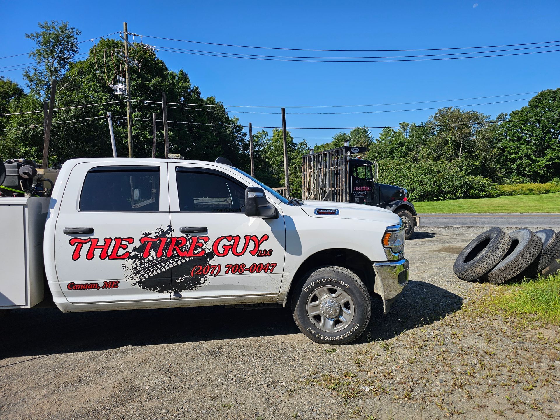 A white truck is parked next to a pile of tires.