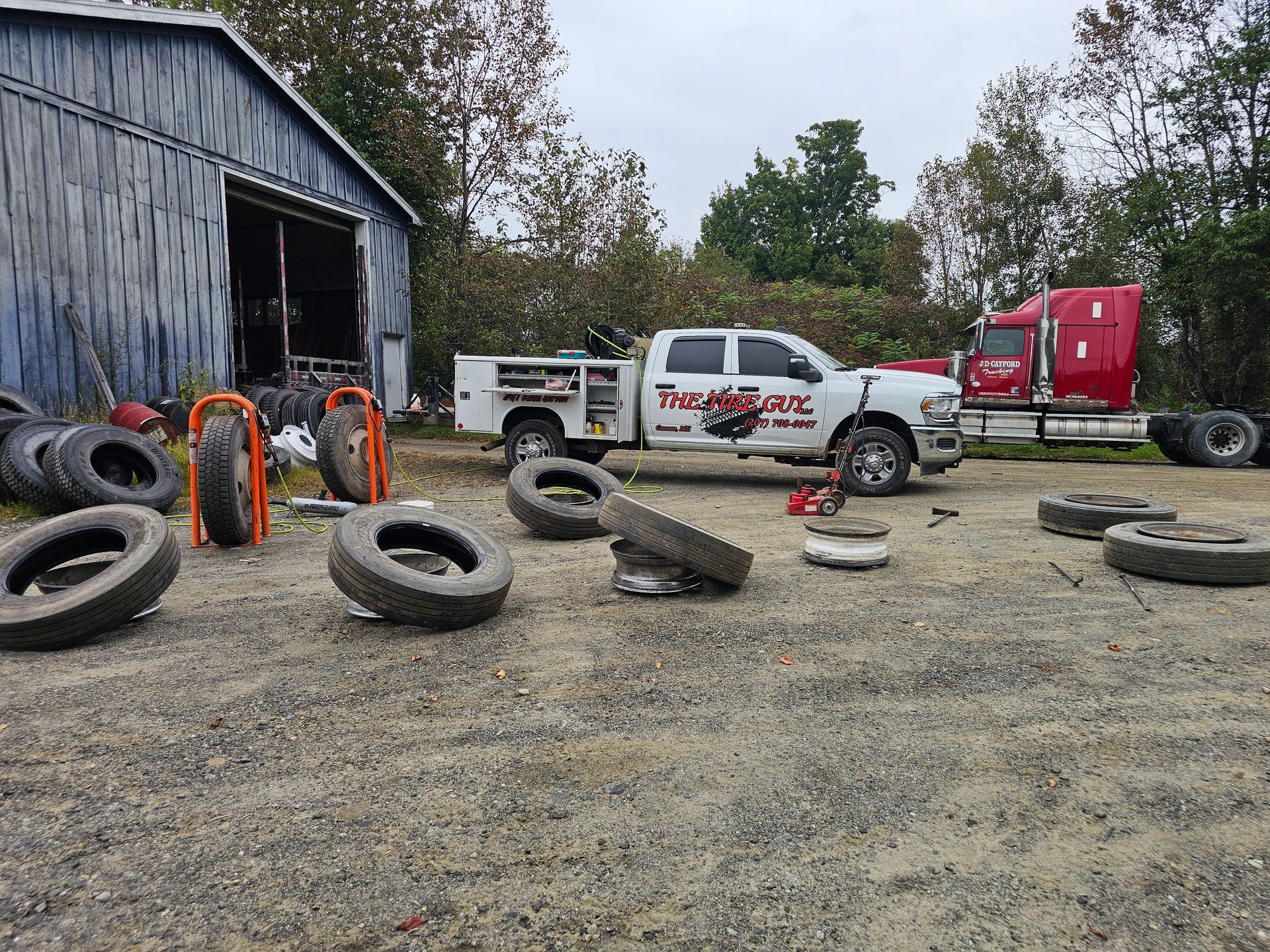 A truck is parked in front of a shed surrounded by tires.