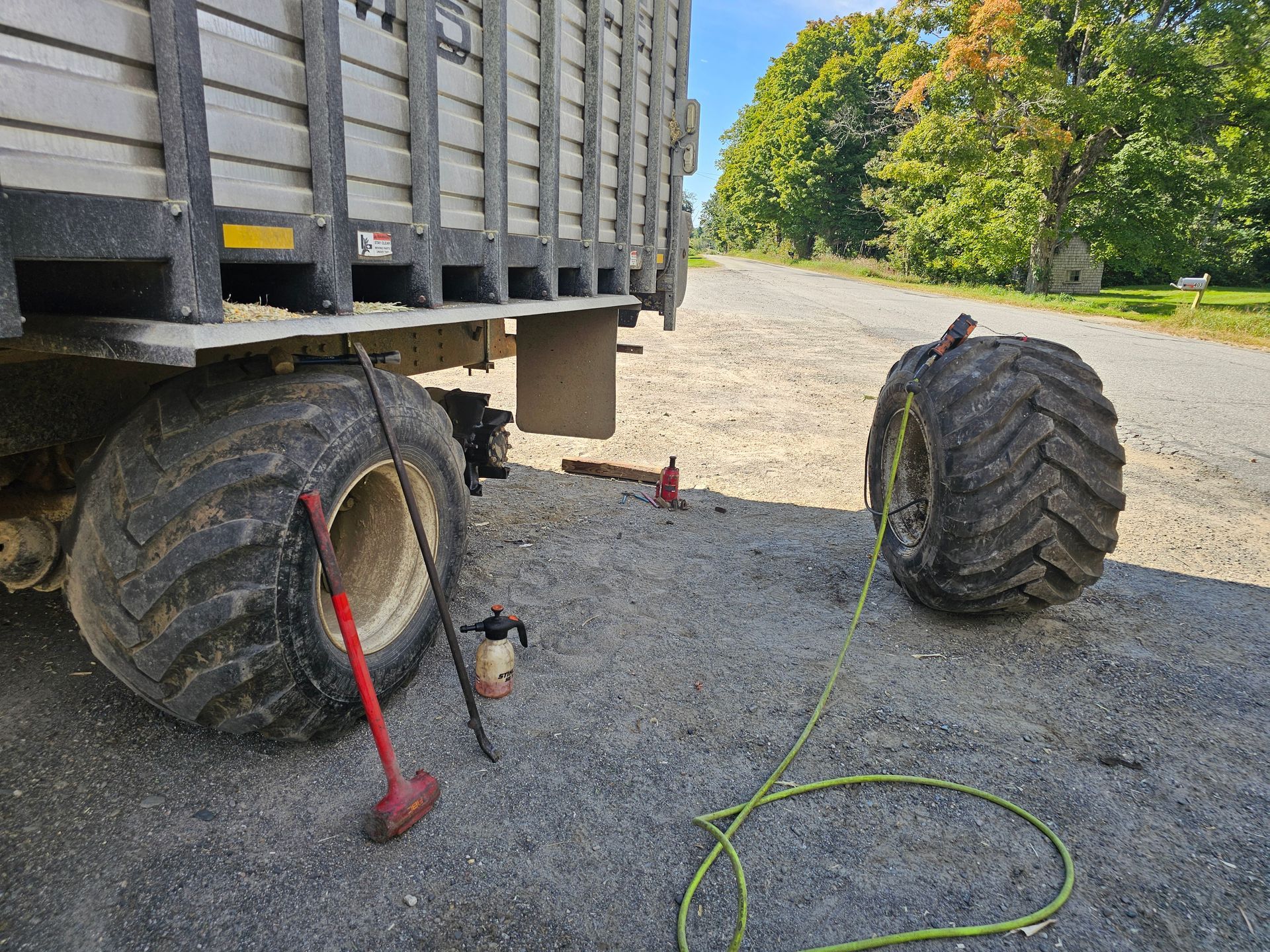 A truck with a flat tire is sitting on the side of the road.