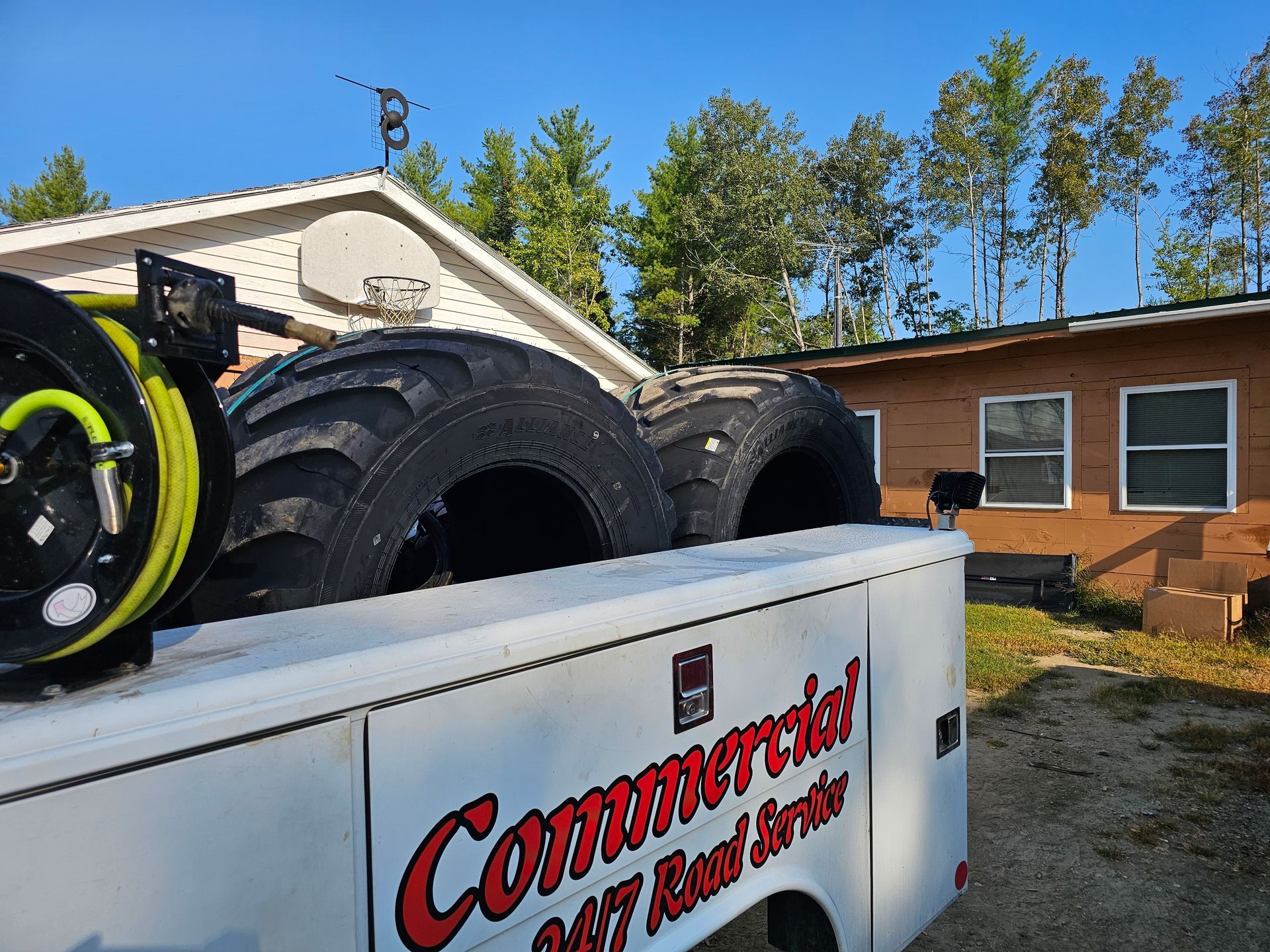 A commercial truck with tires on the back is parked in front of a house.