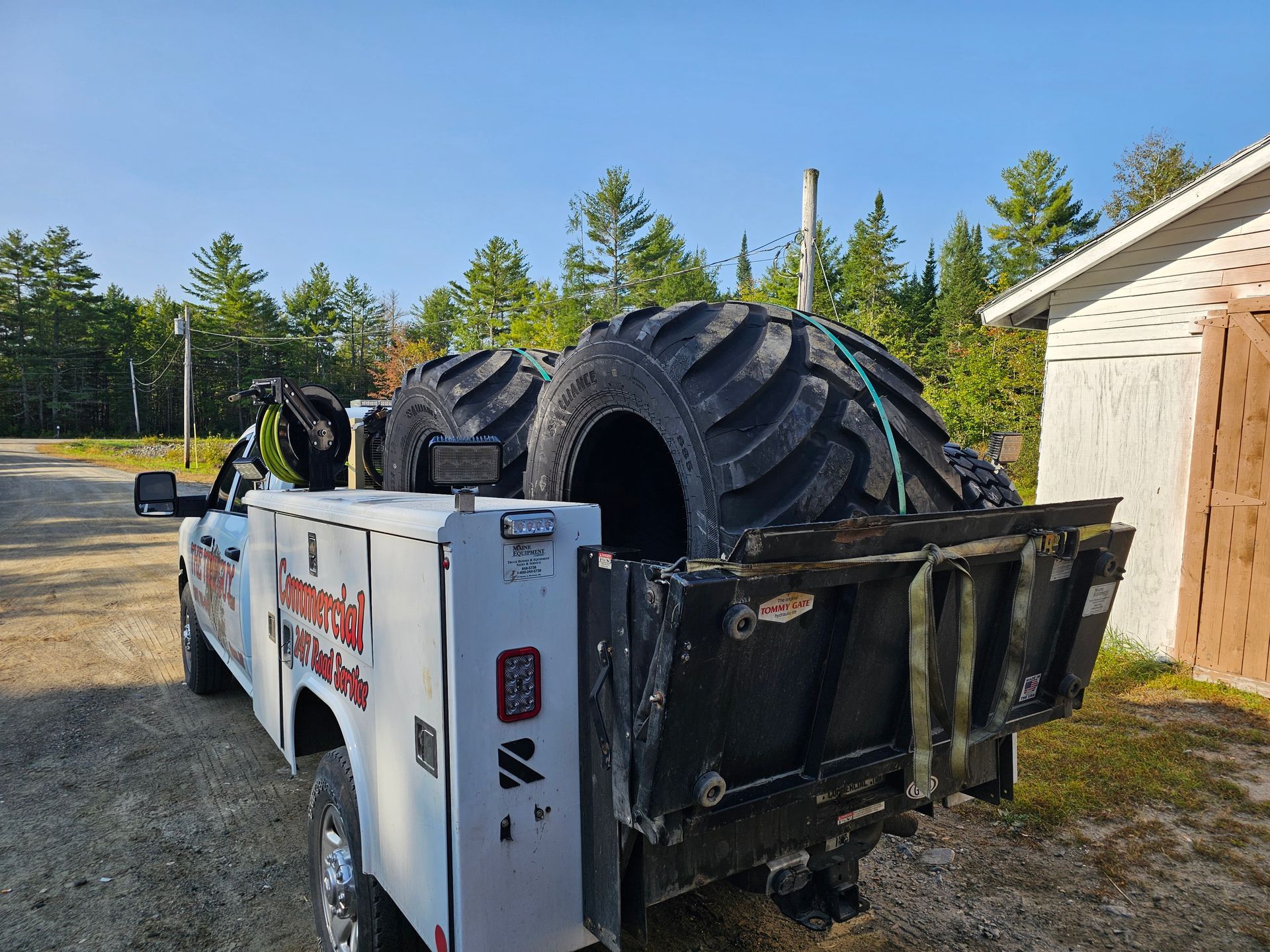 A tow truck is carrying a large tire in the back.