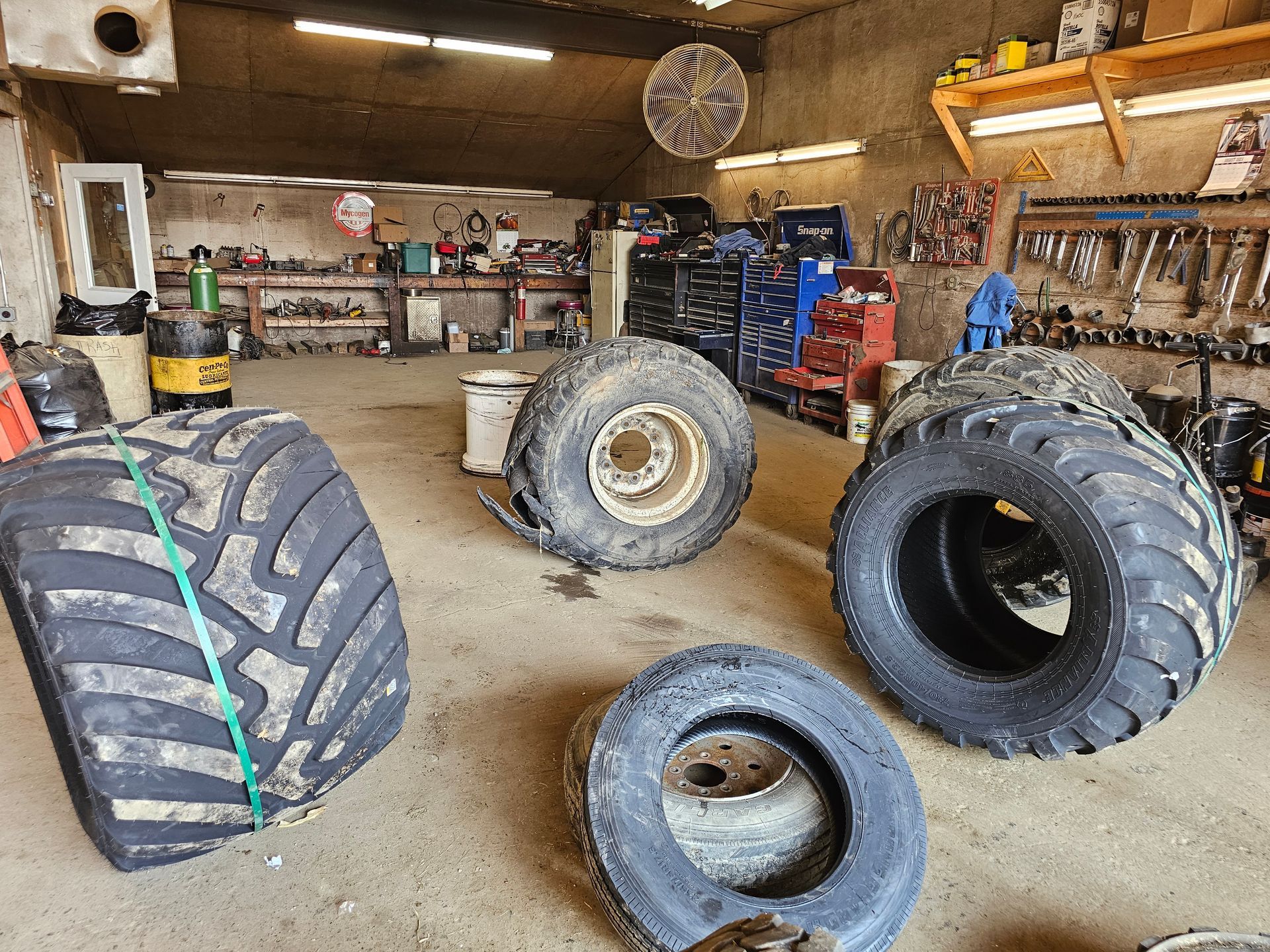 A bunch of tires are sitting on the ground in a garage.