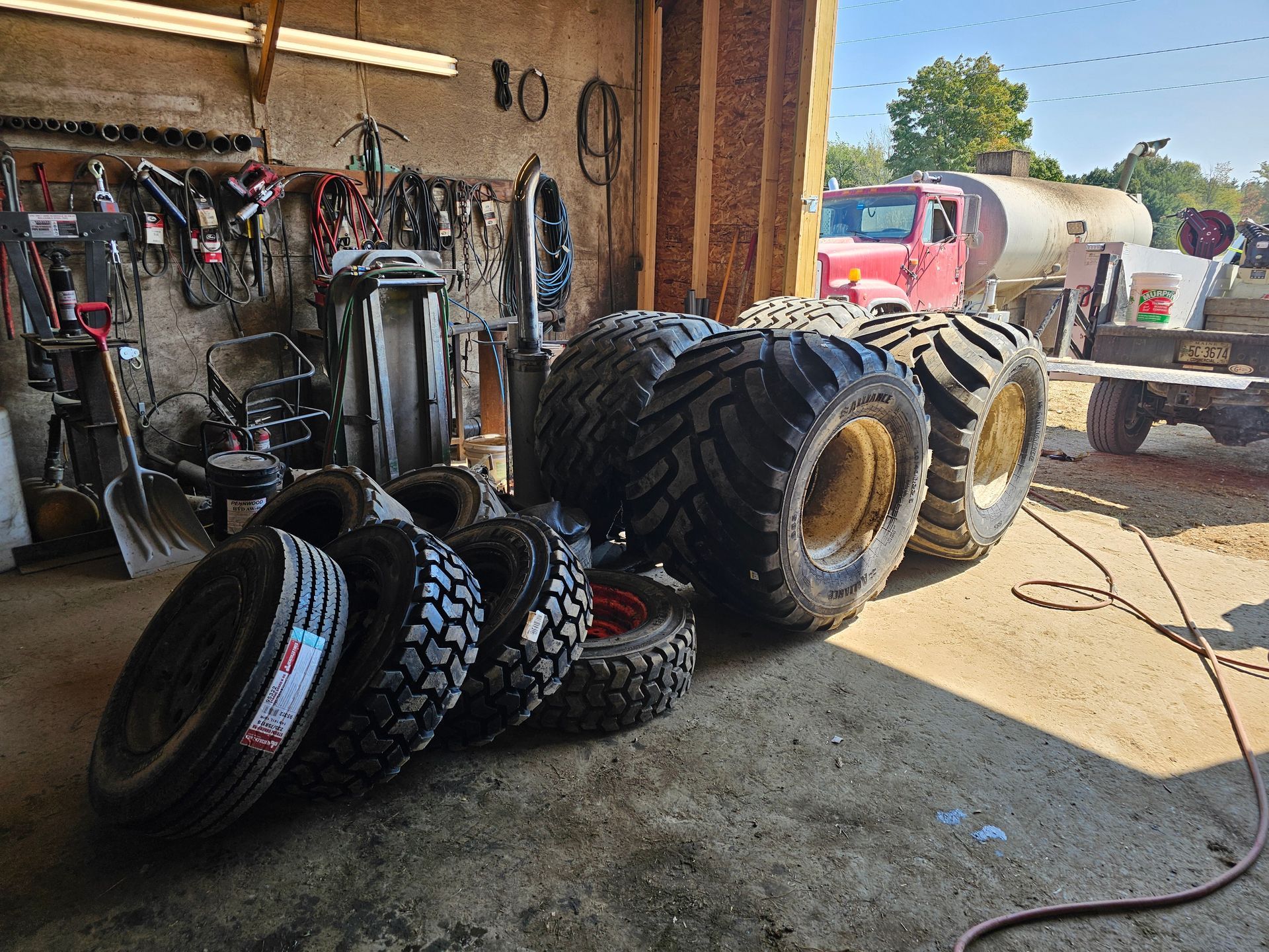 A bunch of tires are stacked on top of each other in a garage.