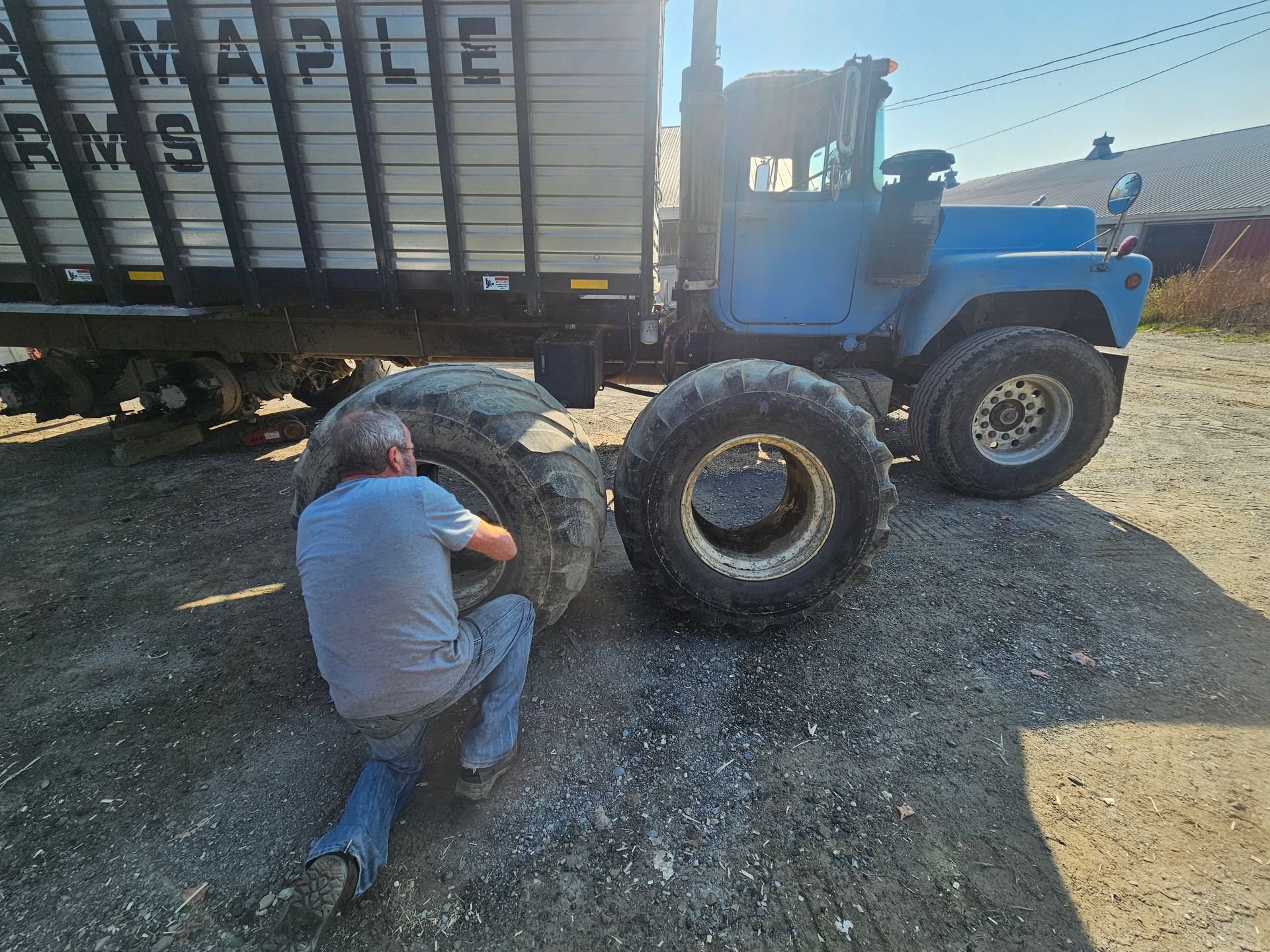 A man is kneeling on the ground next to a tractor.