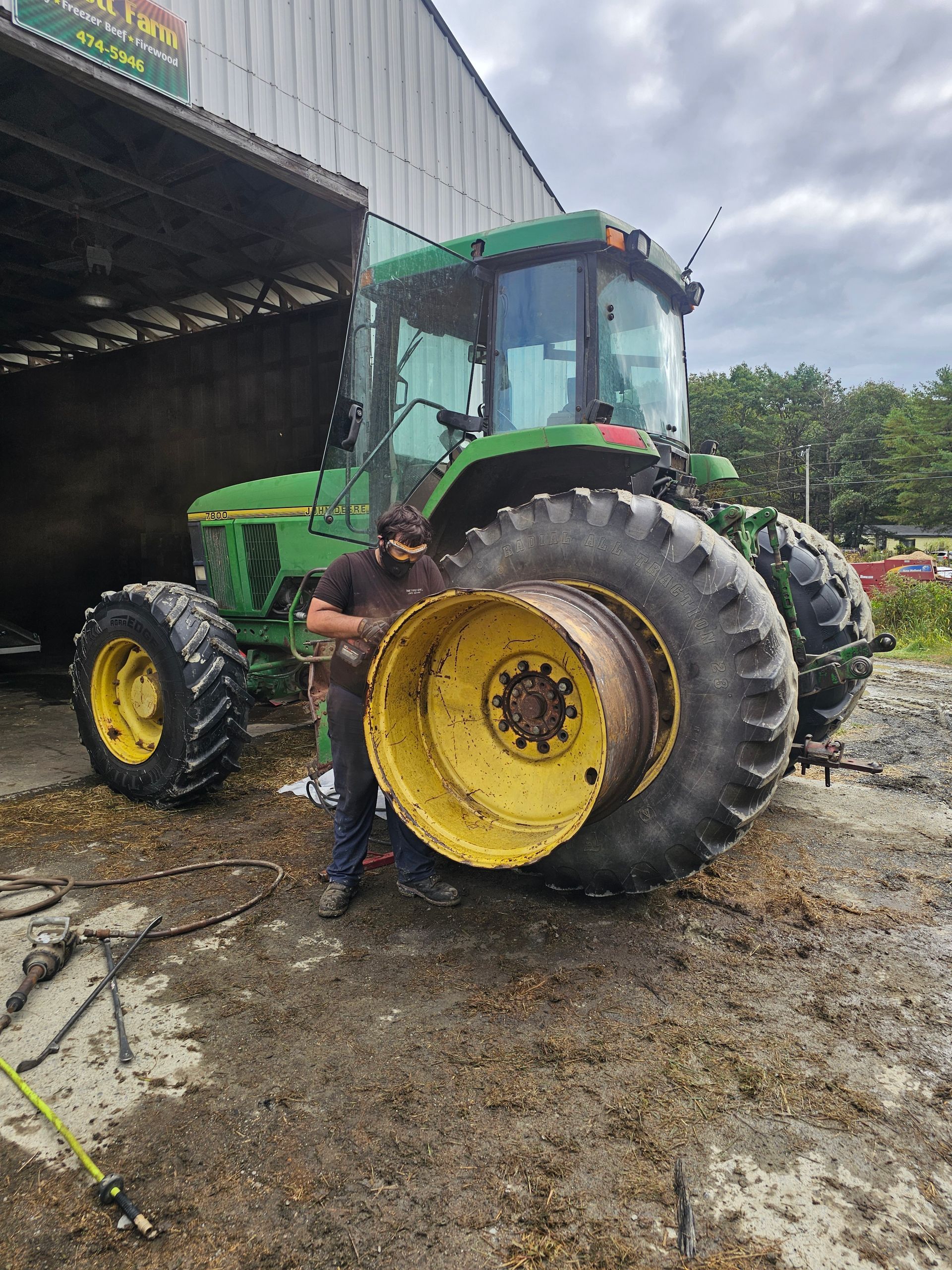 A man is standing in front of a green john deere tractor.