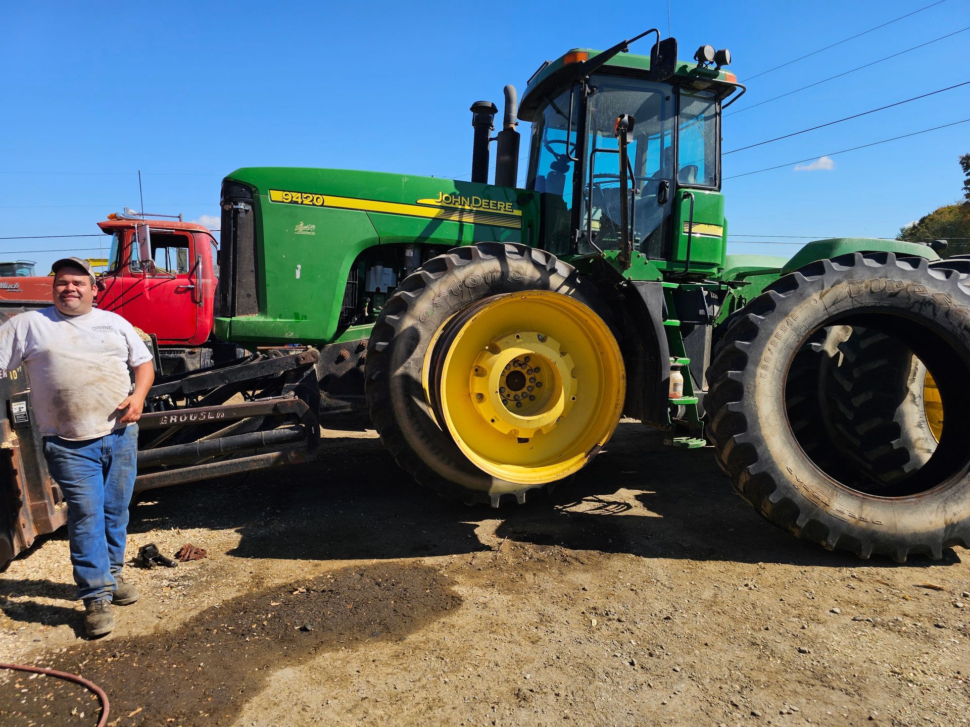 A man is standing in front of a green john deere tractor
